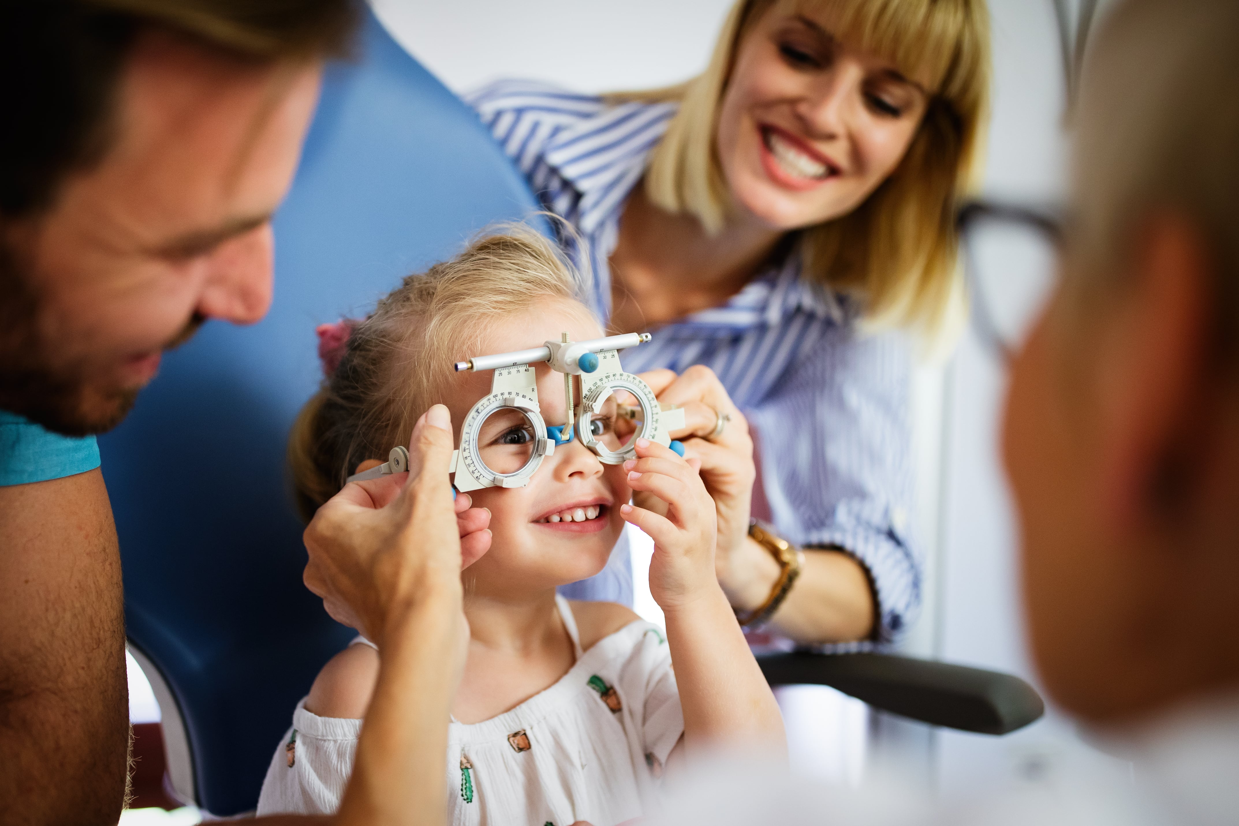 Smiling child getting eye exam with optometrist using trial frame