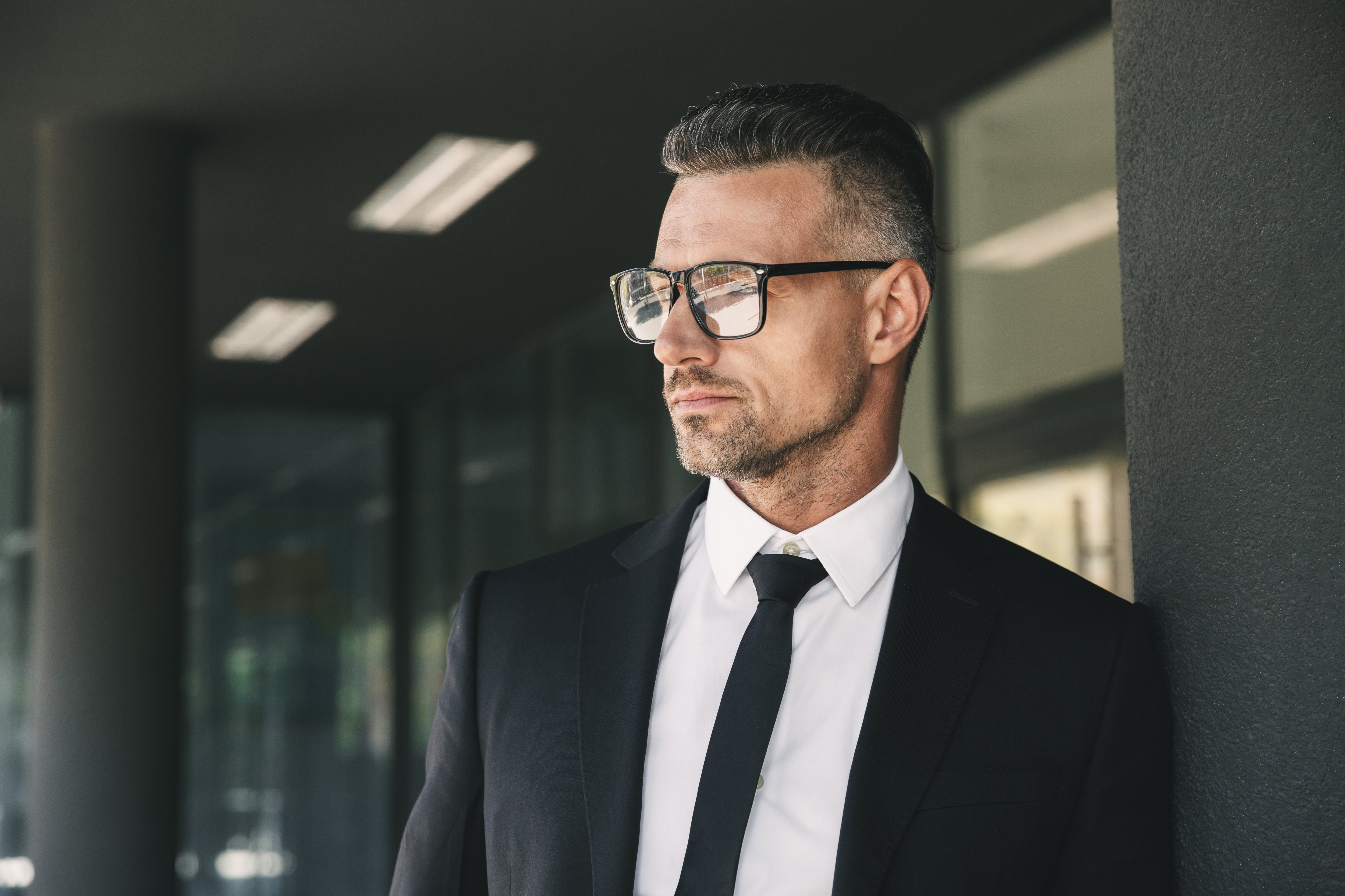 Professional businessman in suit and glasses looking thoughtfully sideways