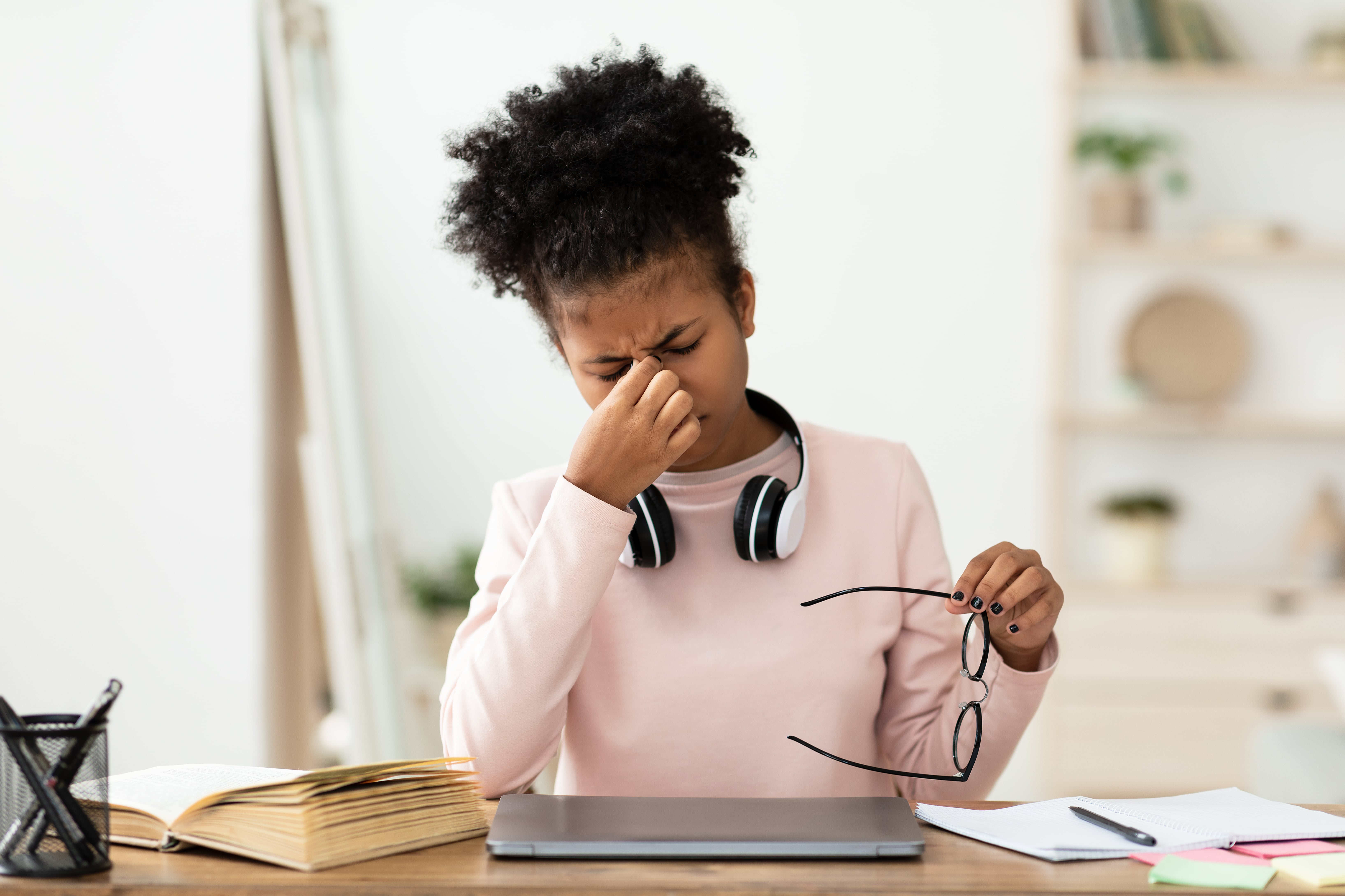 Student feeling stressed while studying with laptop, books, and headphones