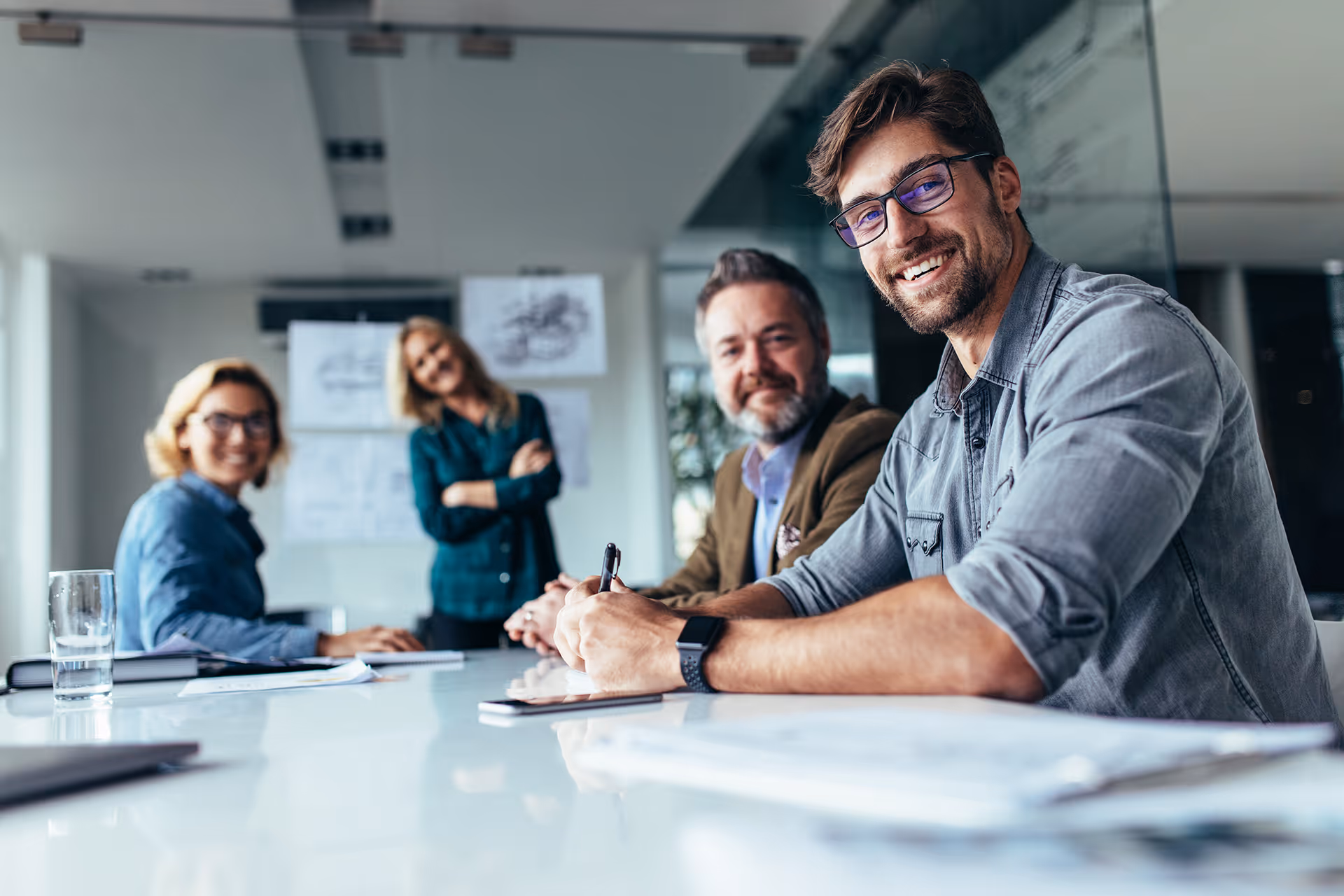 Four people staring at the camera in a meeting room