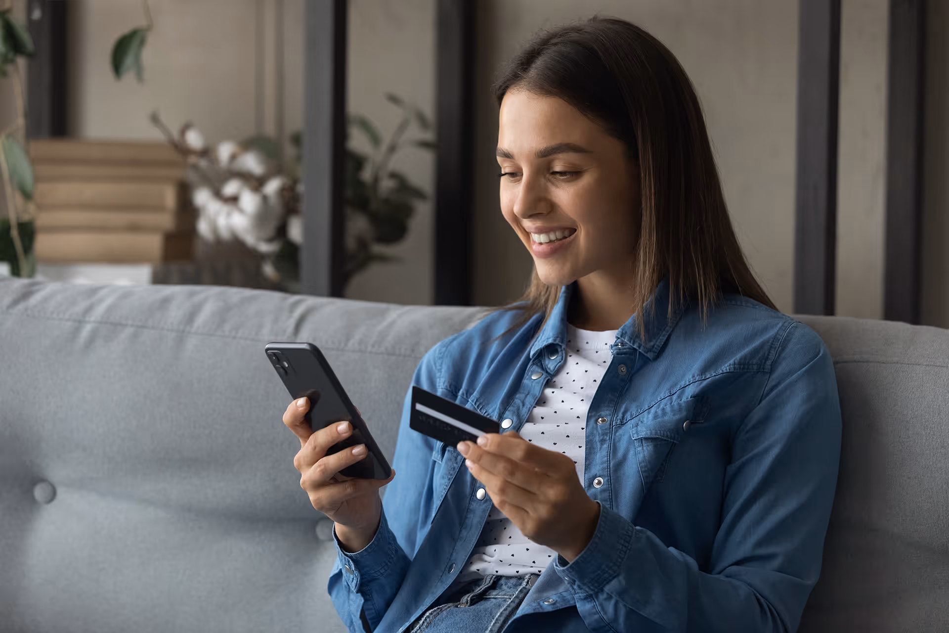 A woman holding a credit card booking a holiday on her phone
