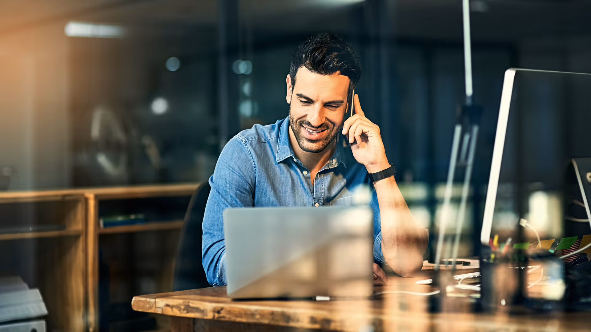 A man on a laptop talking on a mobile phone