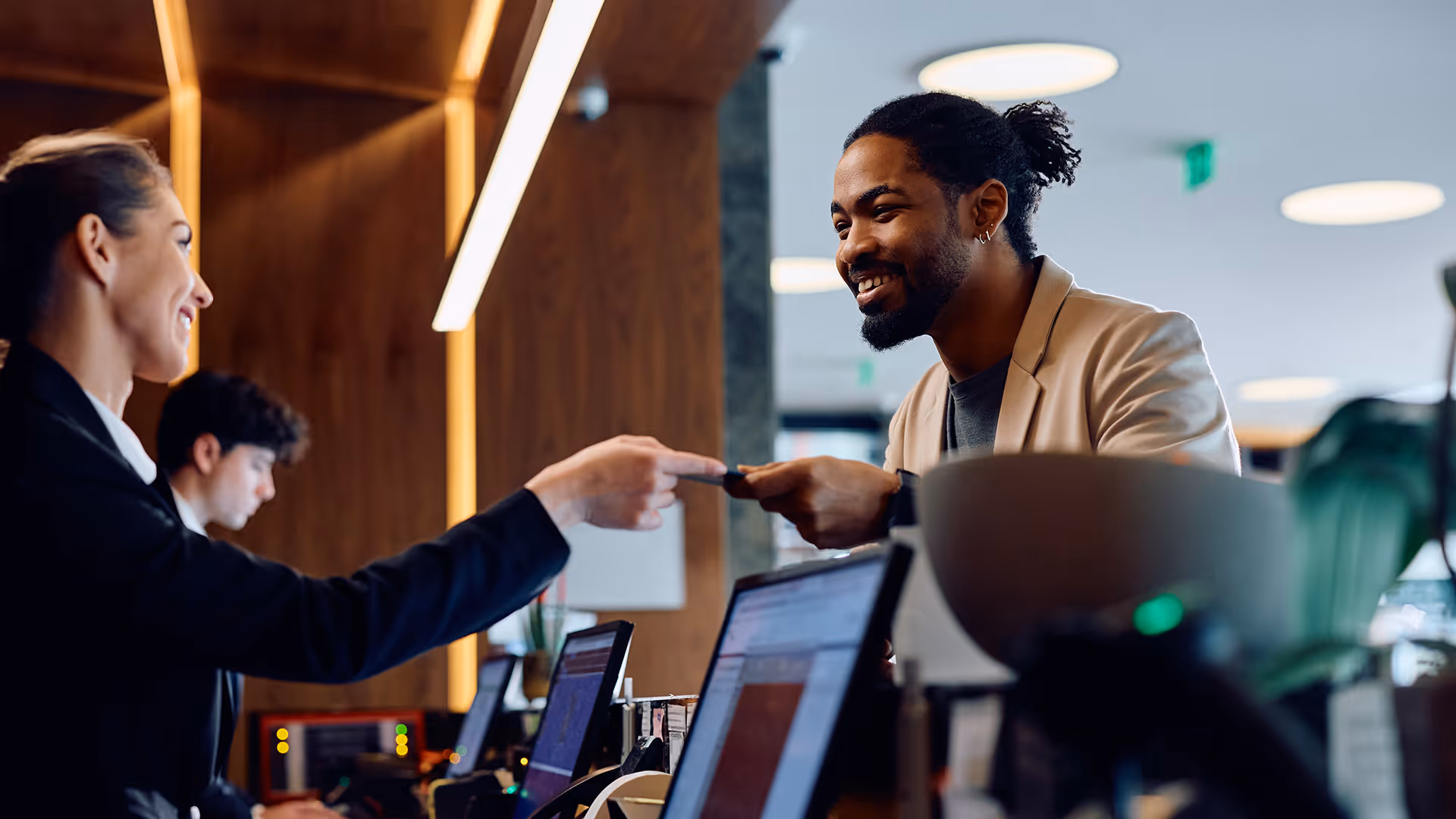 A hotel receptionist being handed a credit card by a guest