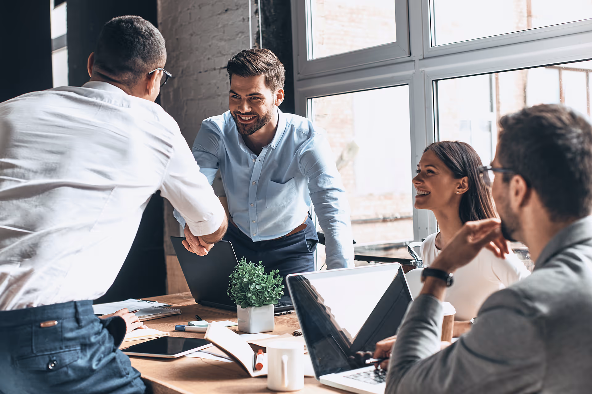 Happy business people smiling and shaking hands — representing dedicated support