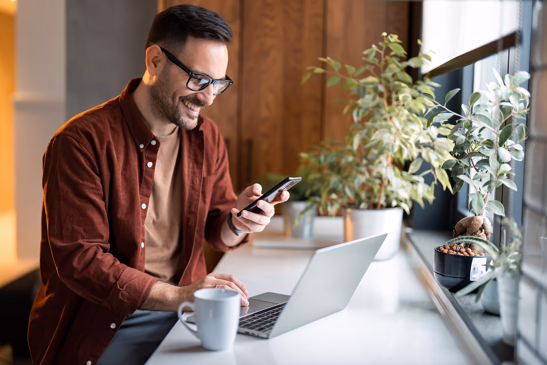 Happy man using a phone and laptop
