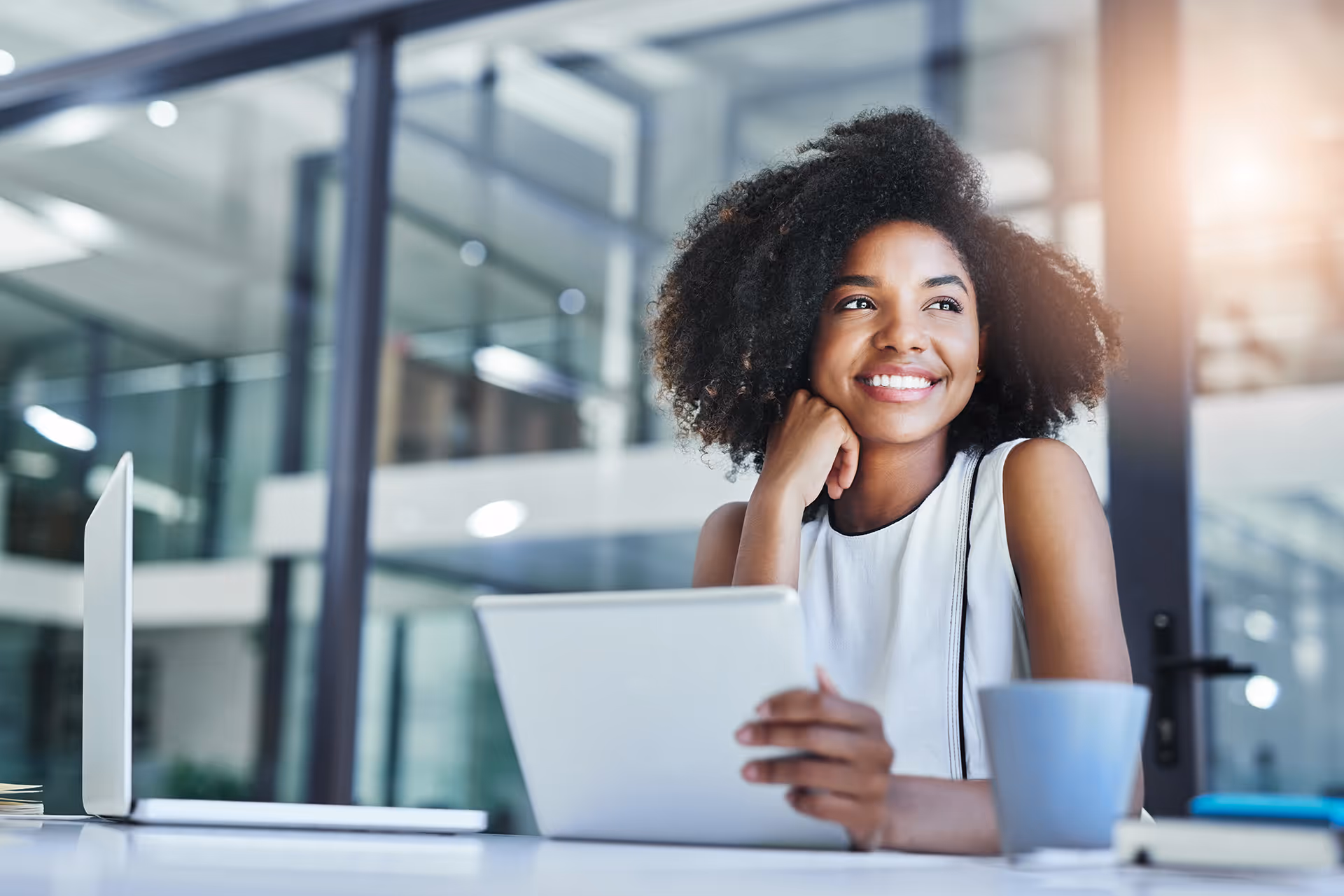 A happy woman holding a tablet and looking into the distance