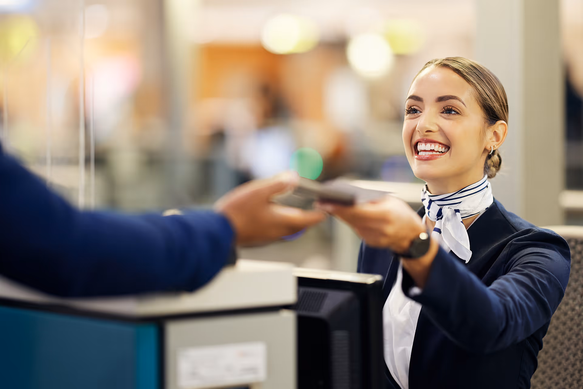 Smiling check-in desk worker handing over passport