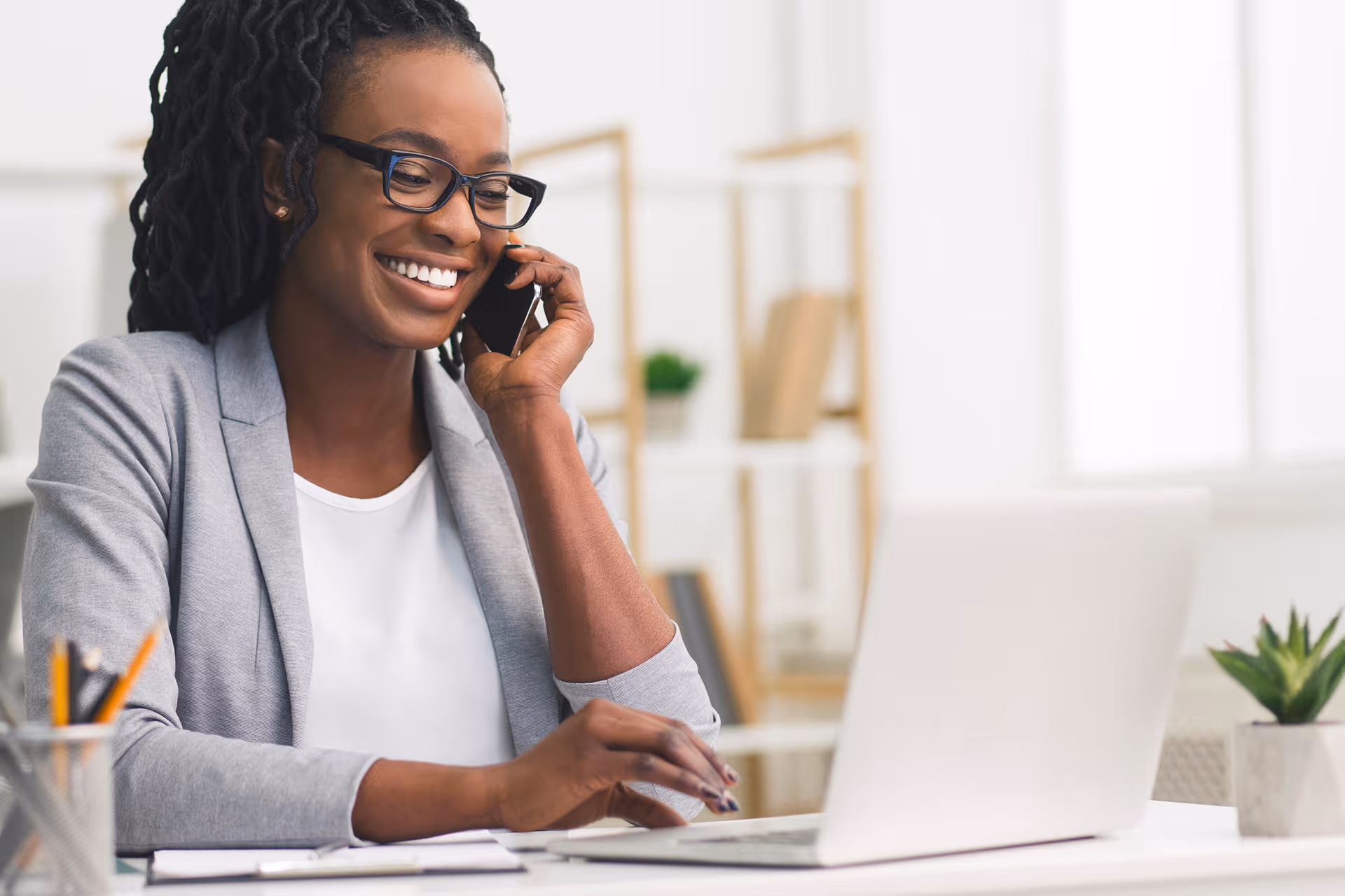 Smiling woman at a desk taking a tour booking over the phone
