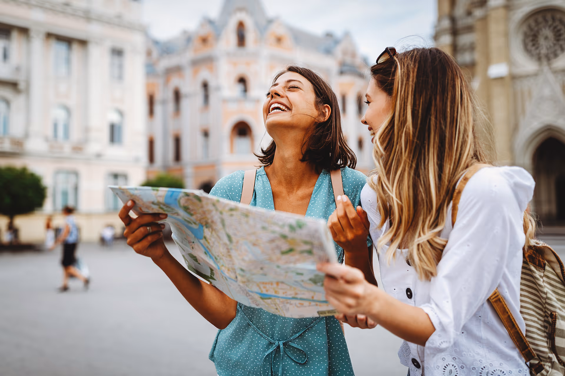 Two women laughing whilst looking at a map — representing experience provider merchant accounts