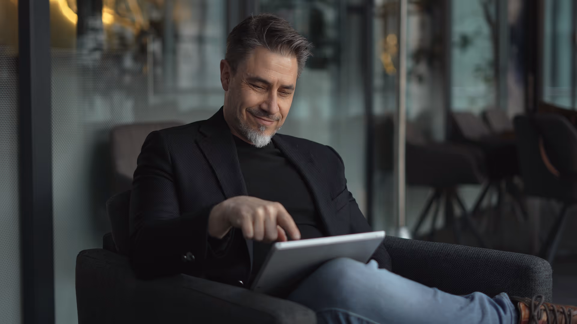 Smiling man sat in an armchair using a tablet