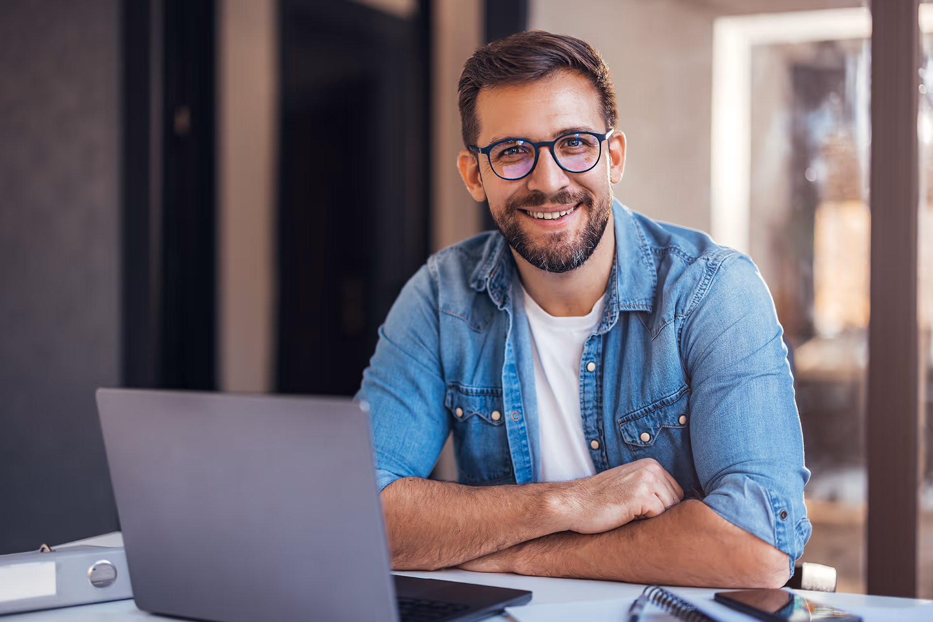 Smiling man sat a a desk looking at the camera