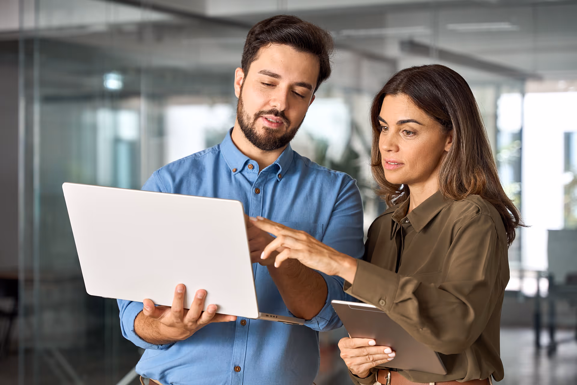 Two people pointing at a screen and discussing