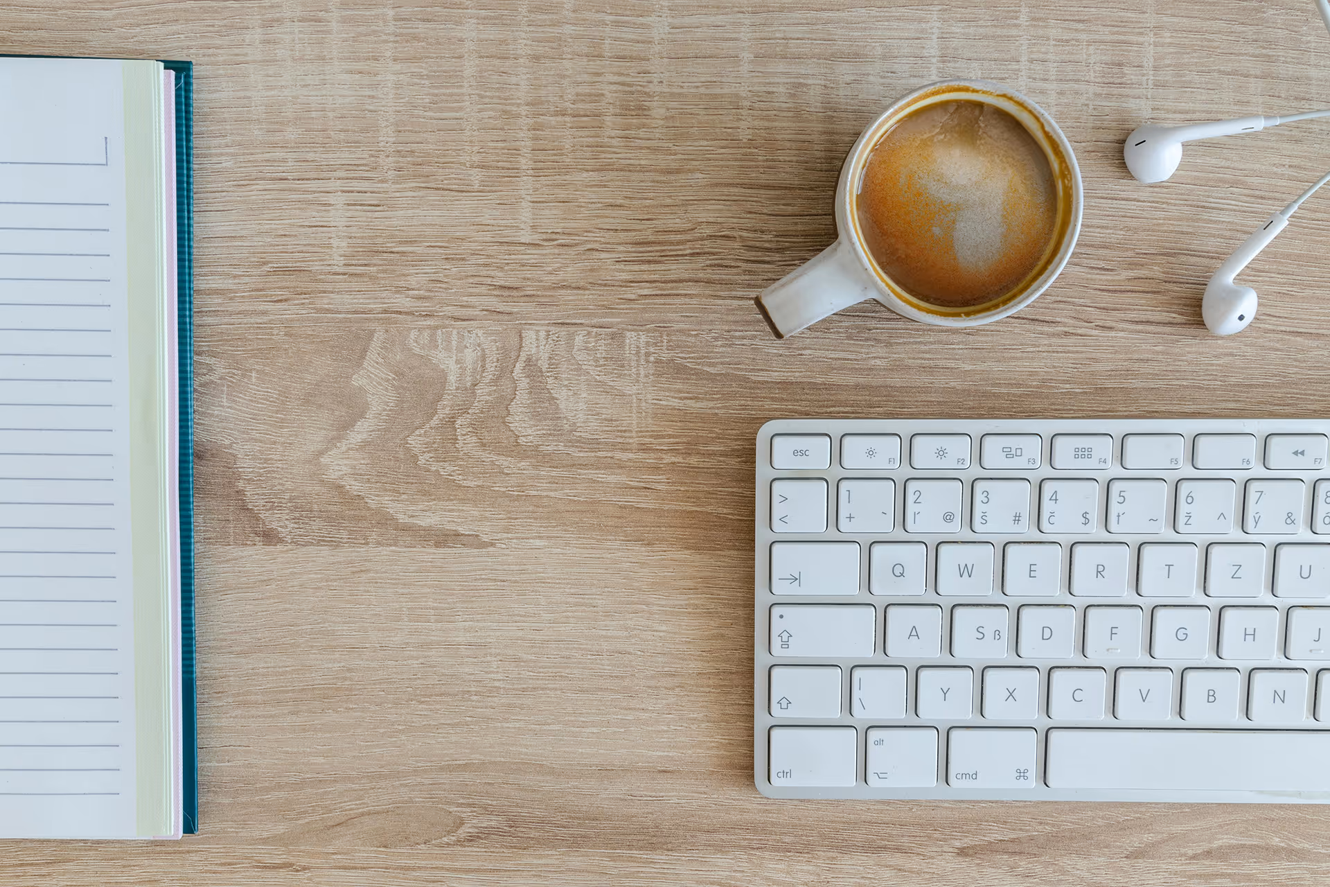 Coffee, notepad, keyboard and headphones on a desk