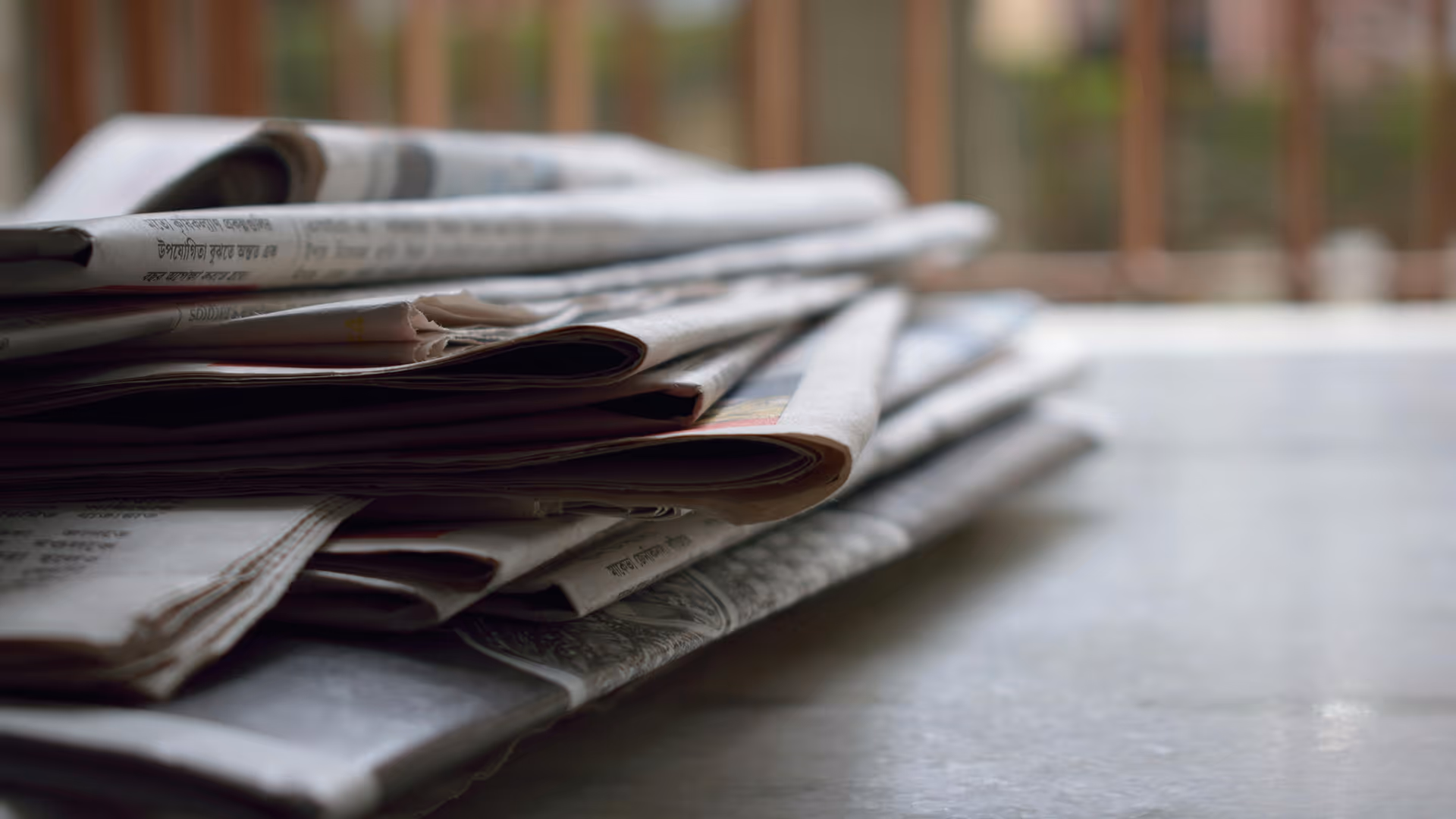 Stack of newspapers on a table, representing press articles