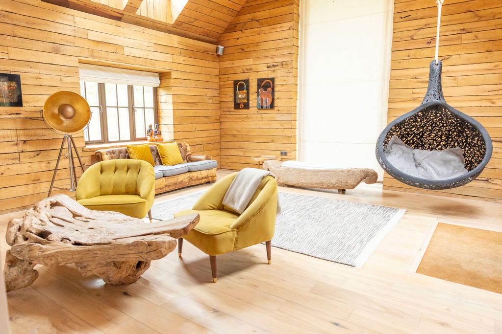 Luxury rustic retreat bedroom with wooden walls, a bed with white linens and pillows, a wooden bench, and a Buddha statue in a yellow alcove above the headboard.