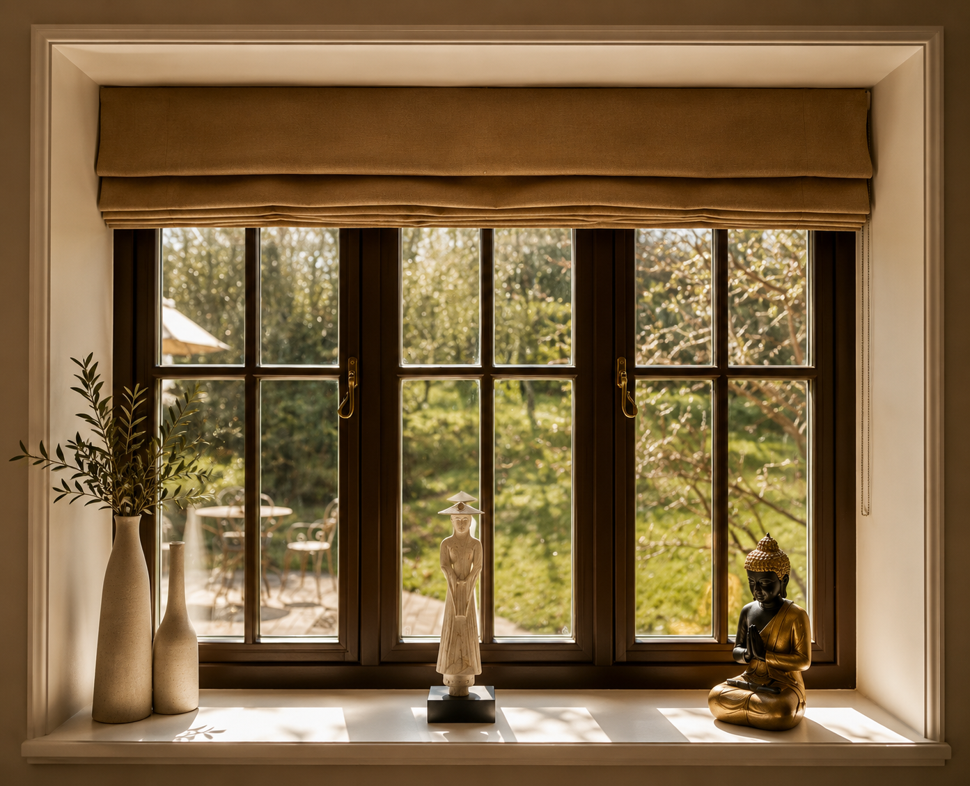 Sunlit window with beige roman shade, three decorative statues on the sill, and a devon retreat green garden visible outside.