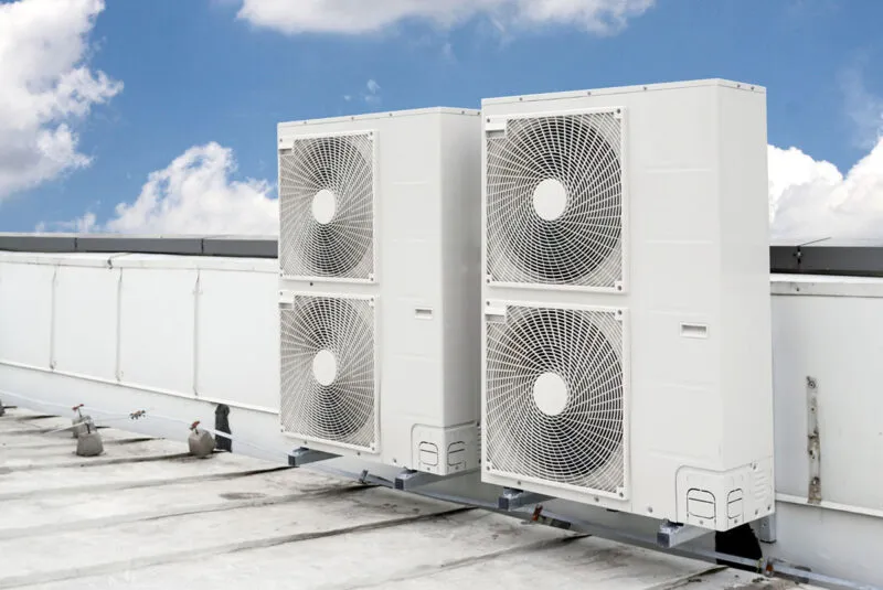 Two industrial air conditioning units on a rooftop against blue sky