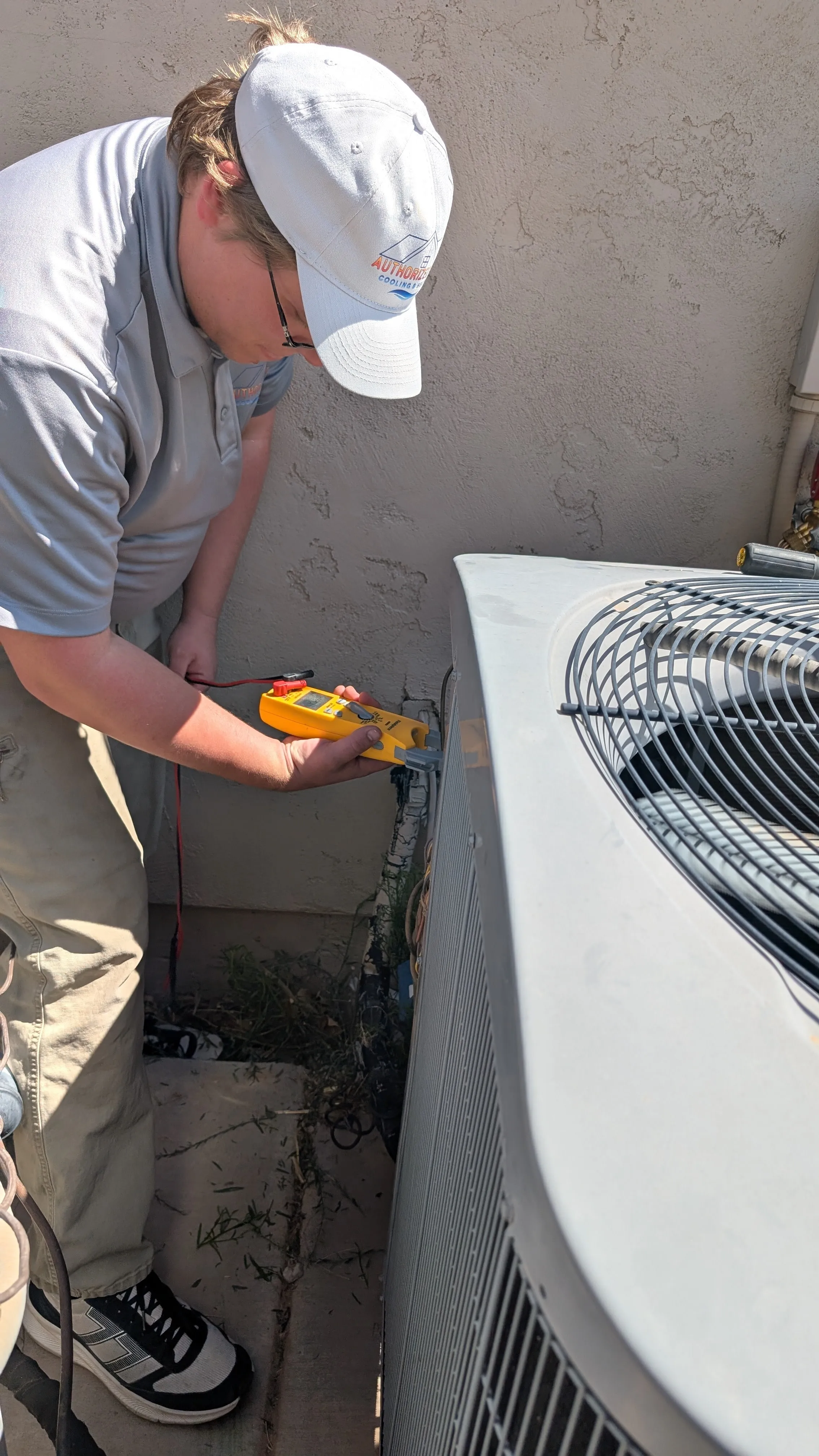 Technician checking HVAC system with yellow electrical testing device