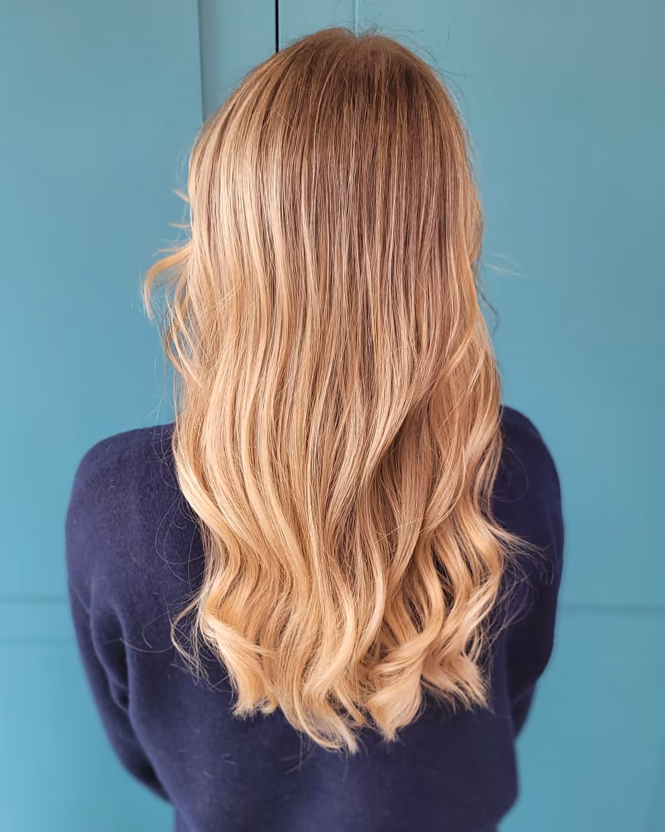 Profil d'un jeune homme avec une coupe de cheveux dégradée courte sur les côtés et cheveux bouclés foncés au-dessus, dans un salon de coiffure moderne.