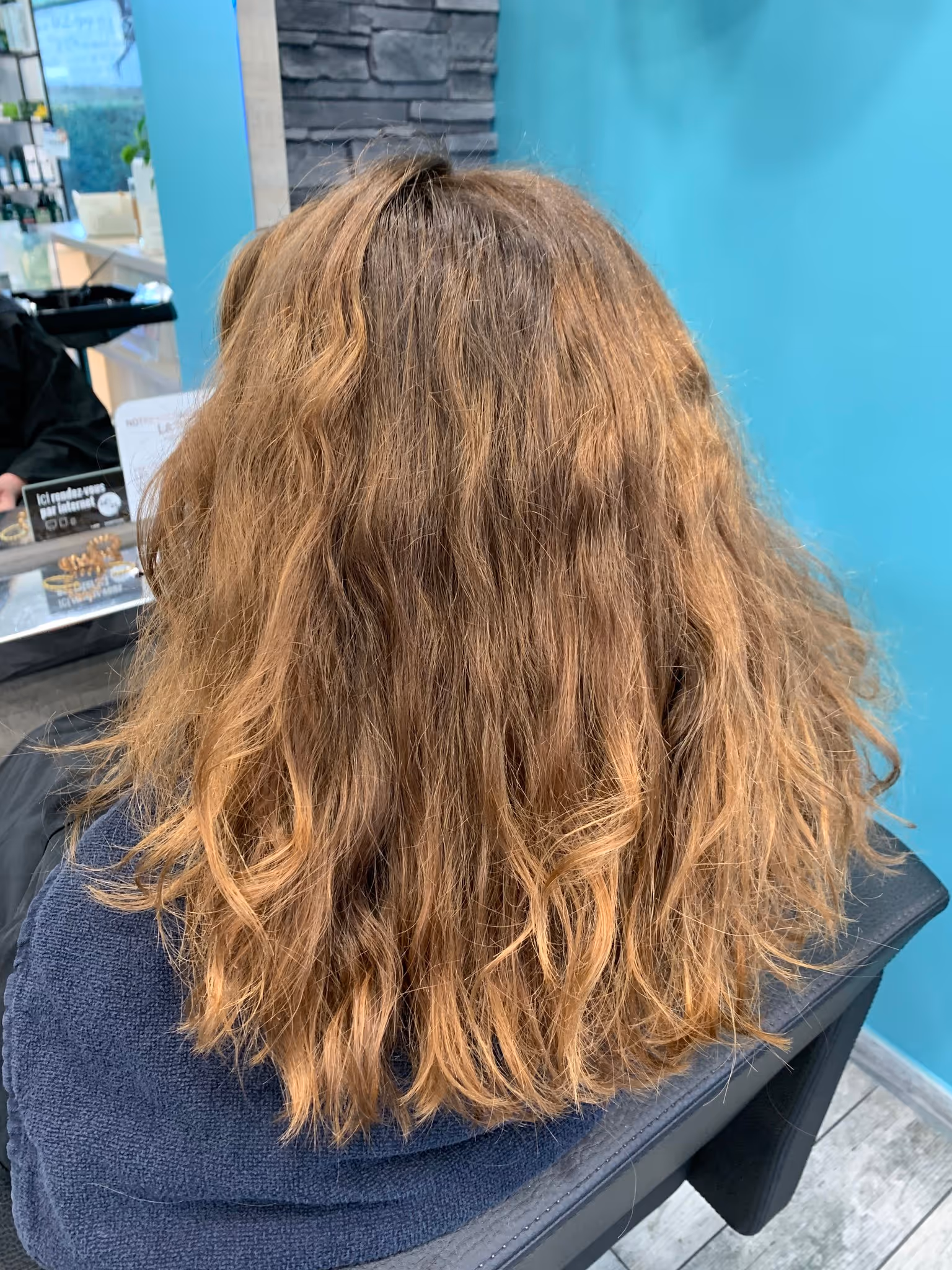 Garçon portant des lunettes et une veste bleue regardant vers la droite dans un salon de coiffure.