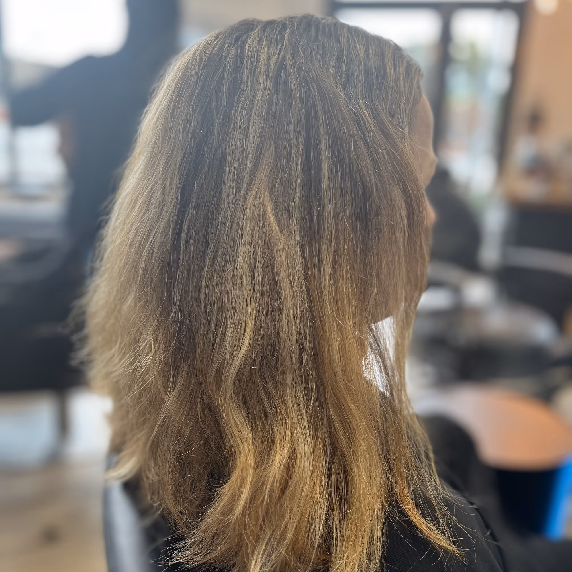 Femme vue de profil avec des cheveux mi-longs ondulés et blond clair.