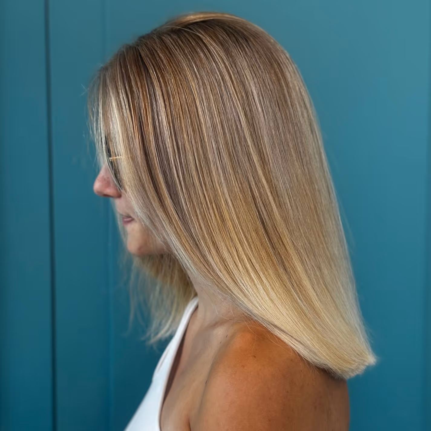 Person assise dans un salon de coiffure avec des cheveux longs bouclés et châtains.