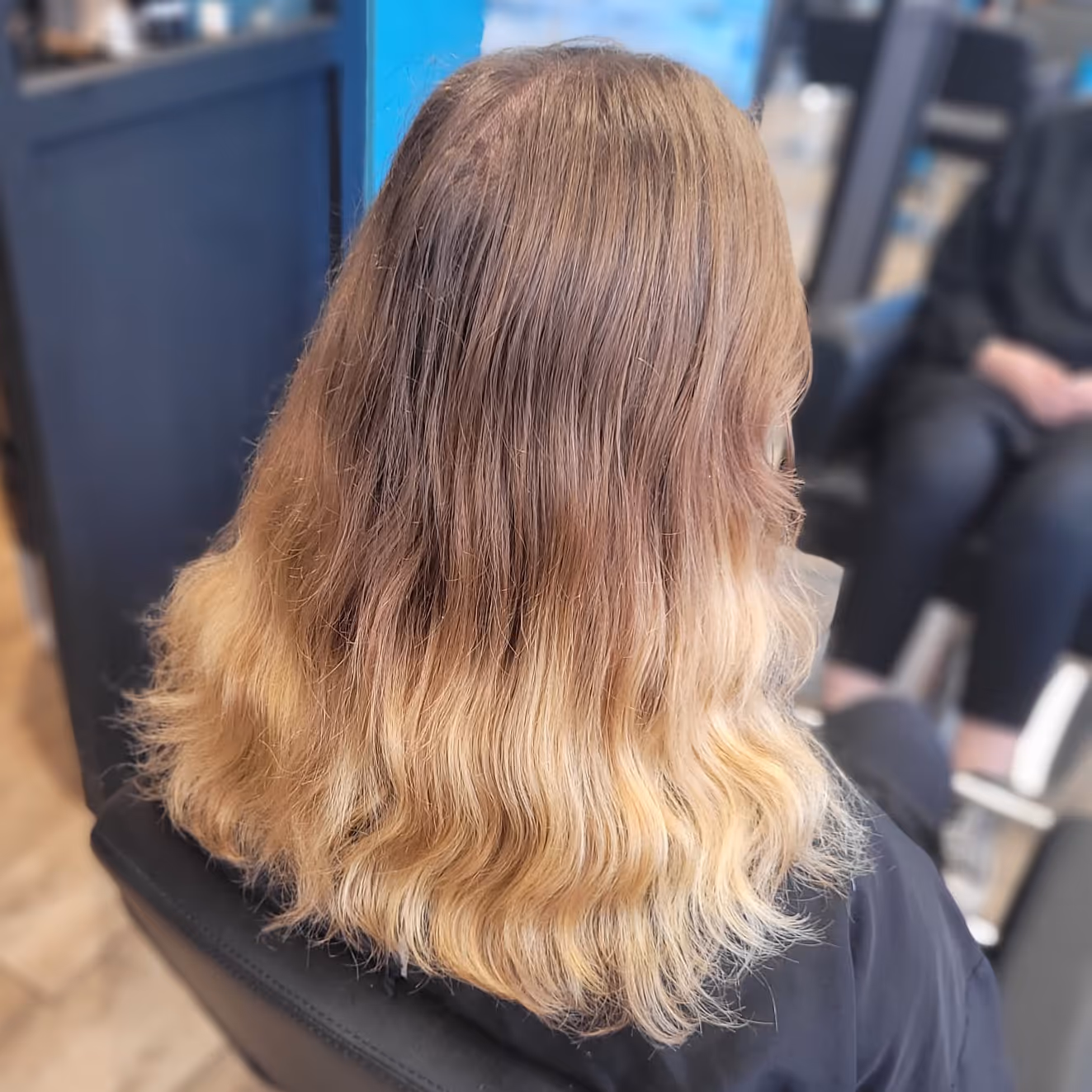 Homme assis dans un salon de coiffure avec une coupe dégradée courte sur les côtés et cheveux texturés sur le dessus.