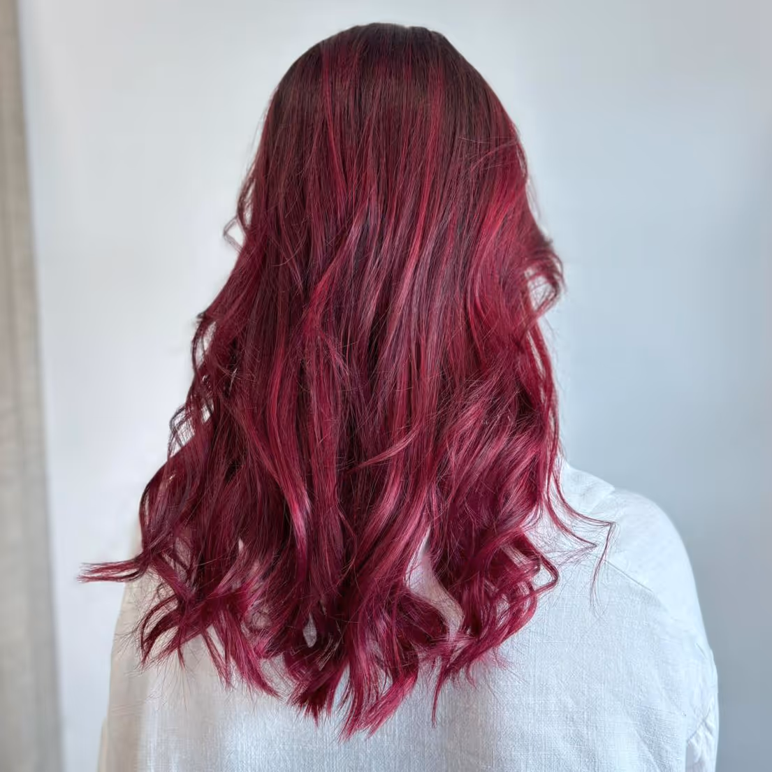Cheveux longs et bruns vus de dos, la personne est assise dans un fauteuil de salon de coiffure.