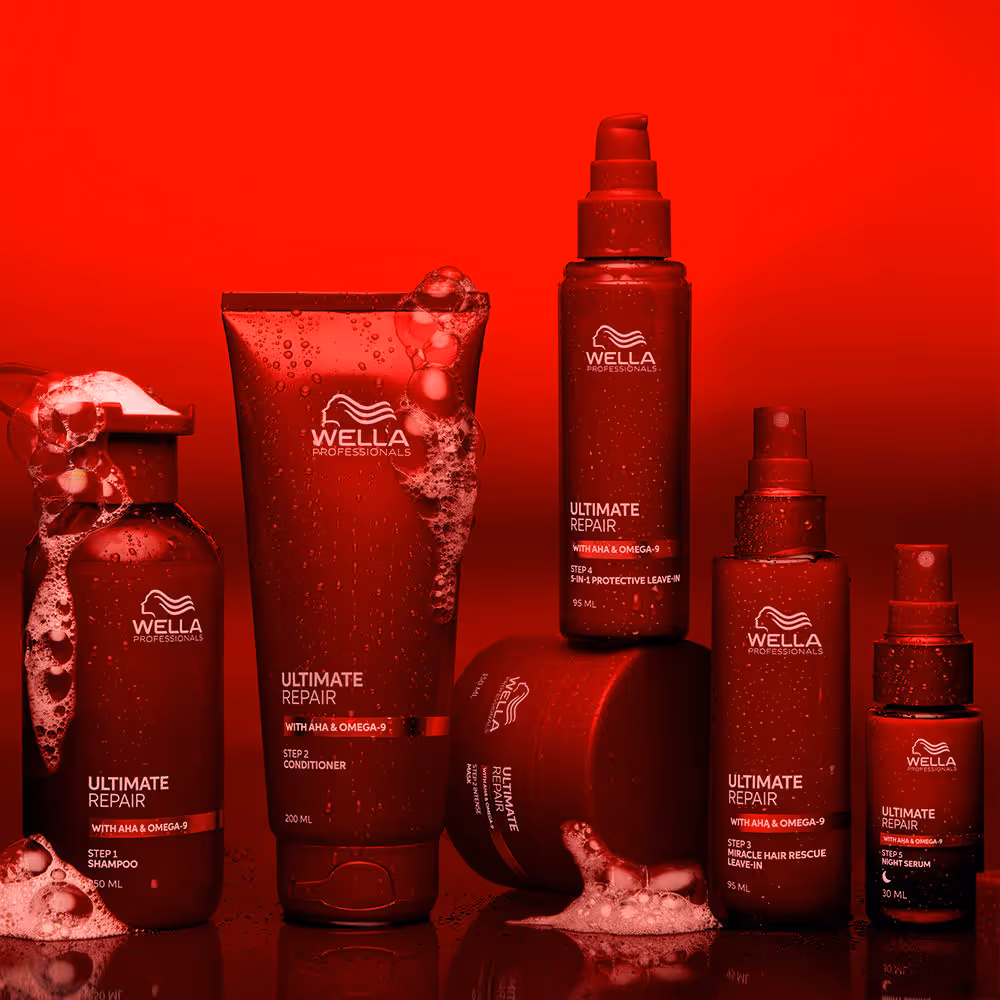 Gamme de produits capillaires rouges Wella Professionals Ultimate Repair avec mousse sur fond rouge.