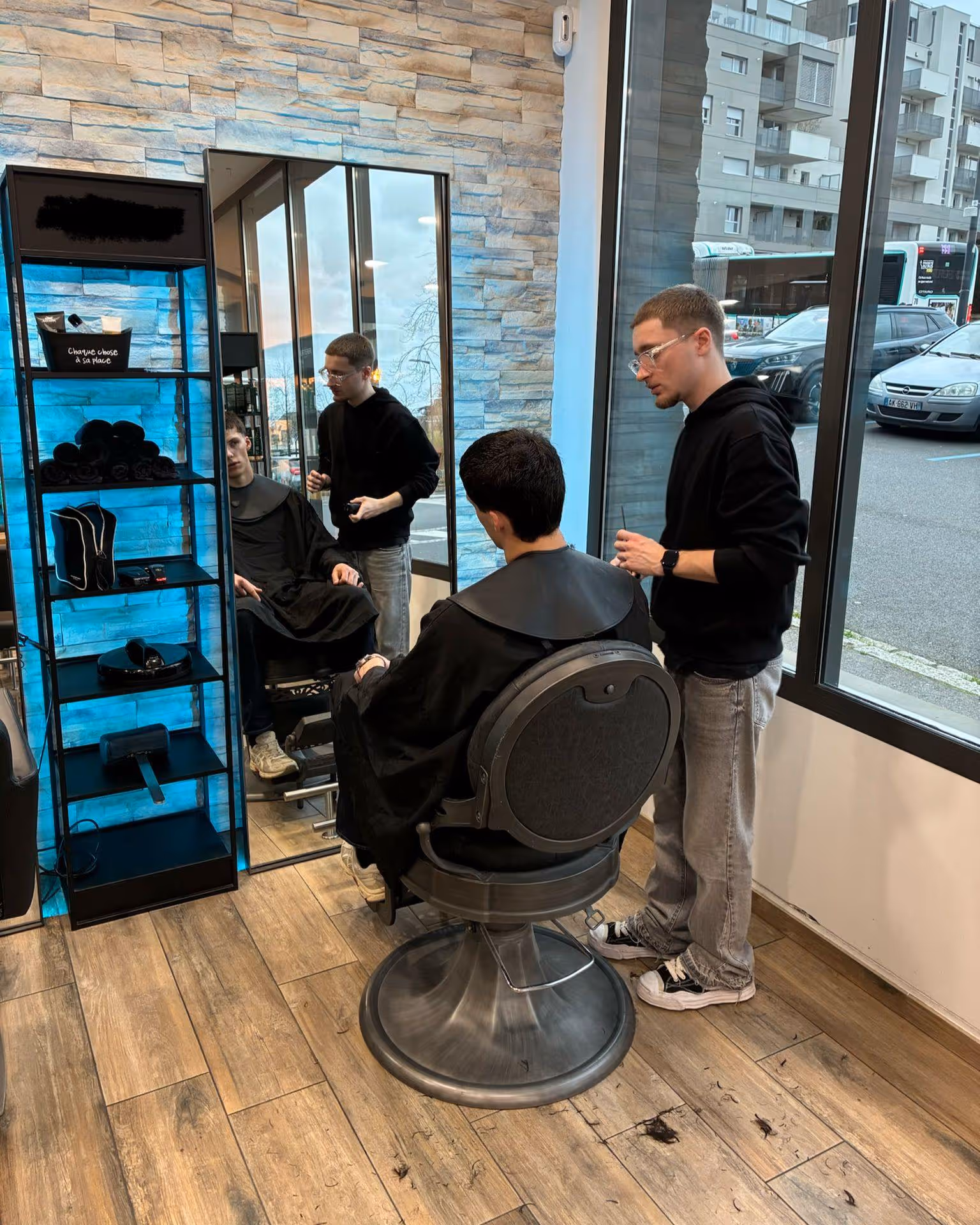 Profil d'un jeune homme avec une coupe de cheveux courte sur les côtés et bouclée sur le dessus dans un salon de coiffure.