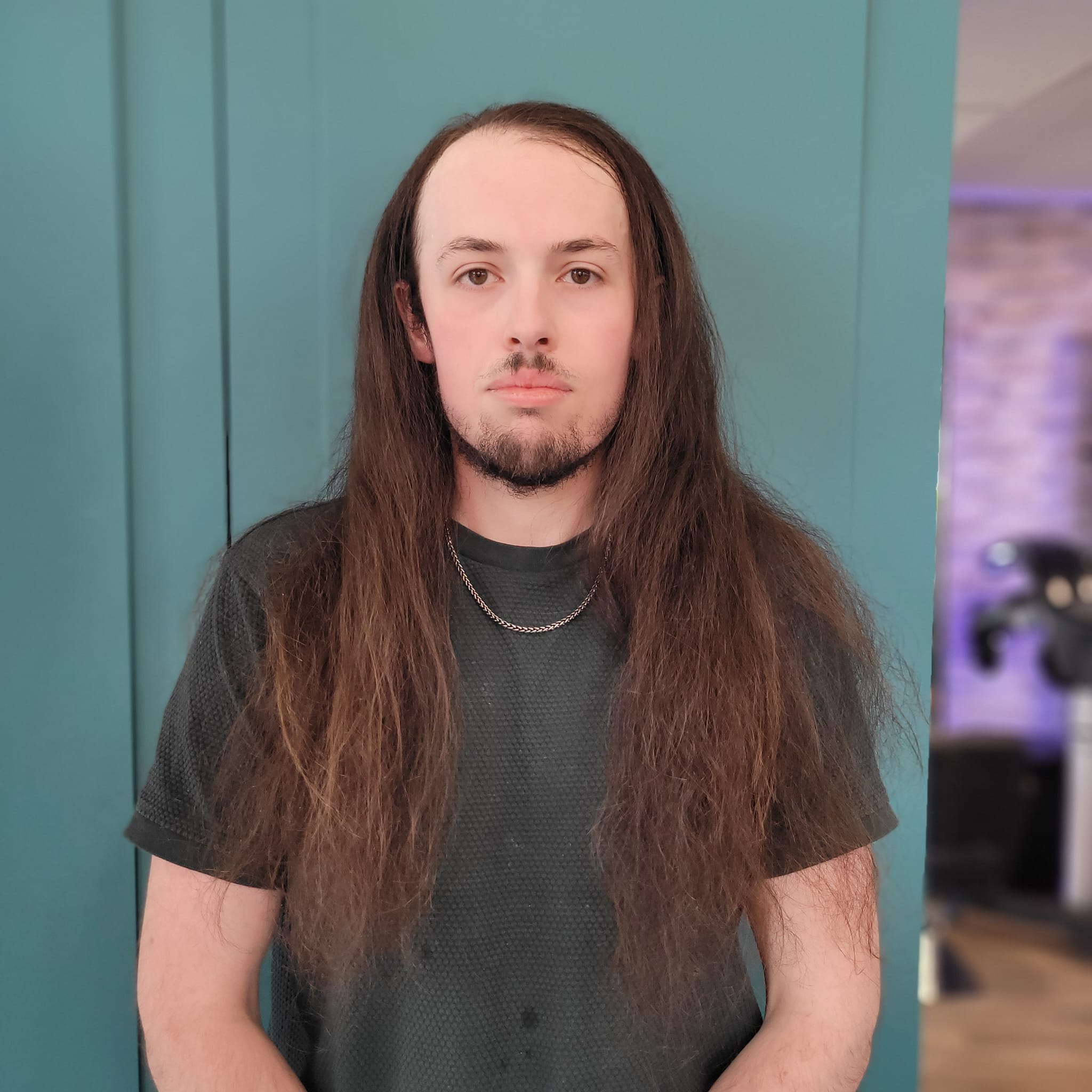 Person assise dans un salon de coiffure avec de longs cheveux bouclés marron clair.