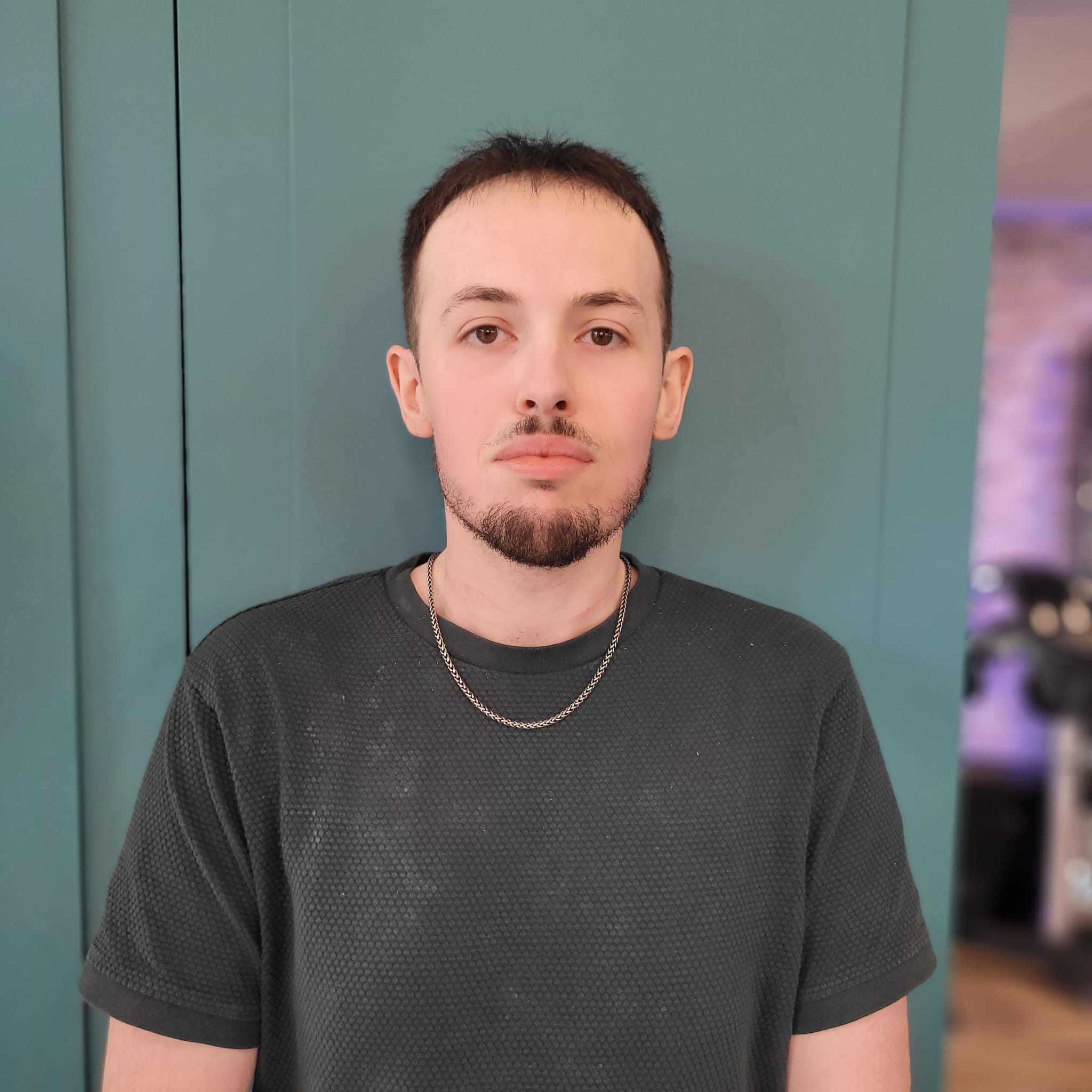 Jeune homme de profil avec une coupe dégradée et des boucles sur le dessus dans un salon de coiffure moderne.