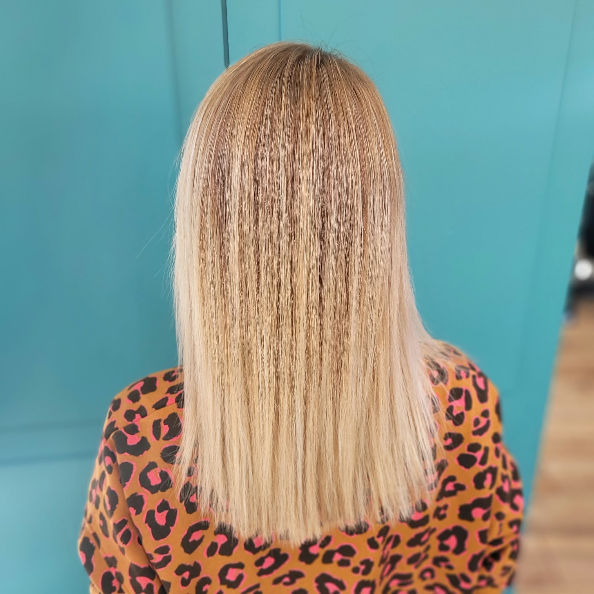 Cheveux longs bouclés avec des mèches blondes vues de dos sur une personne portant un haut rayé blanc et noir.