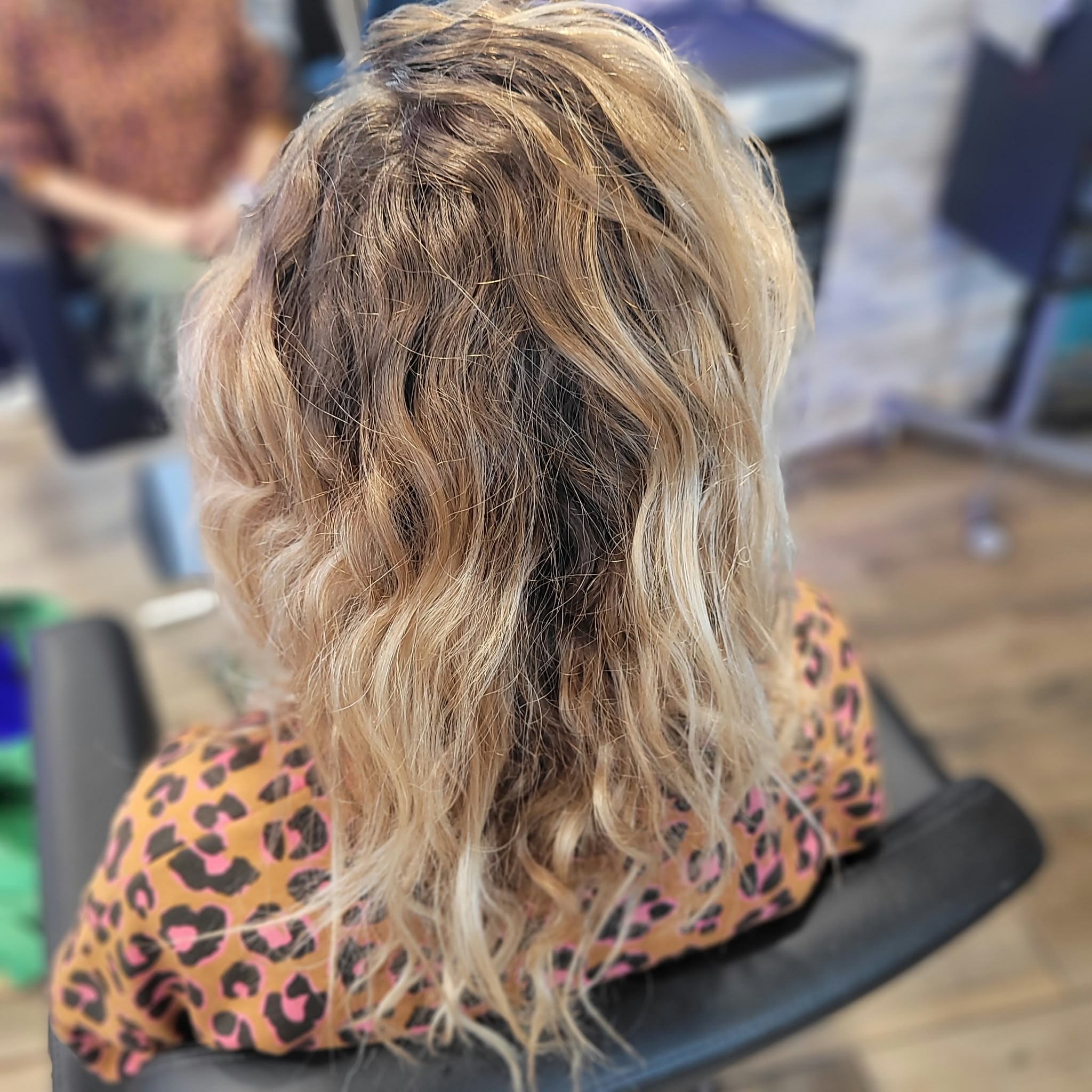 Cheveux longs, épais et ondulés vus de dos dans un salon de coiffure.