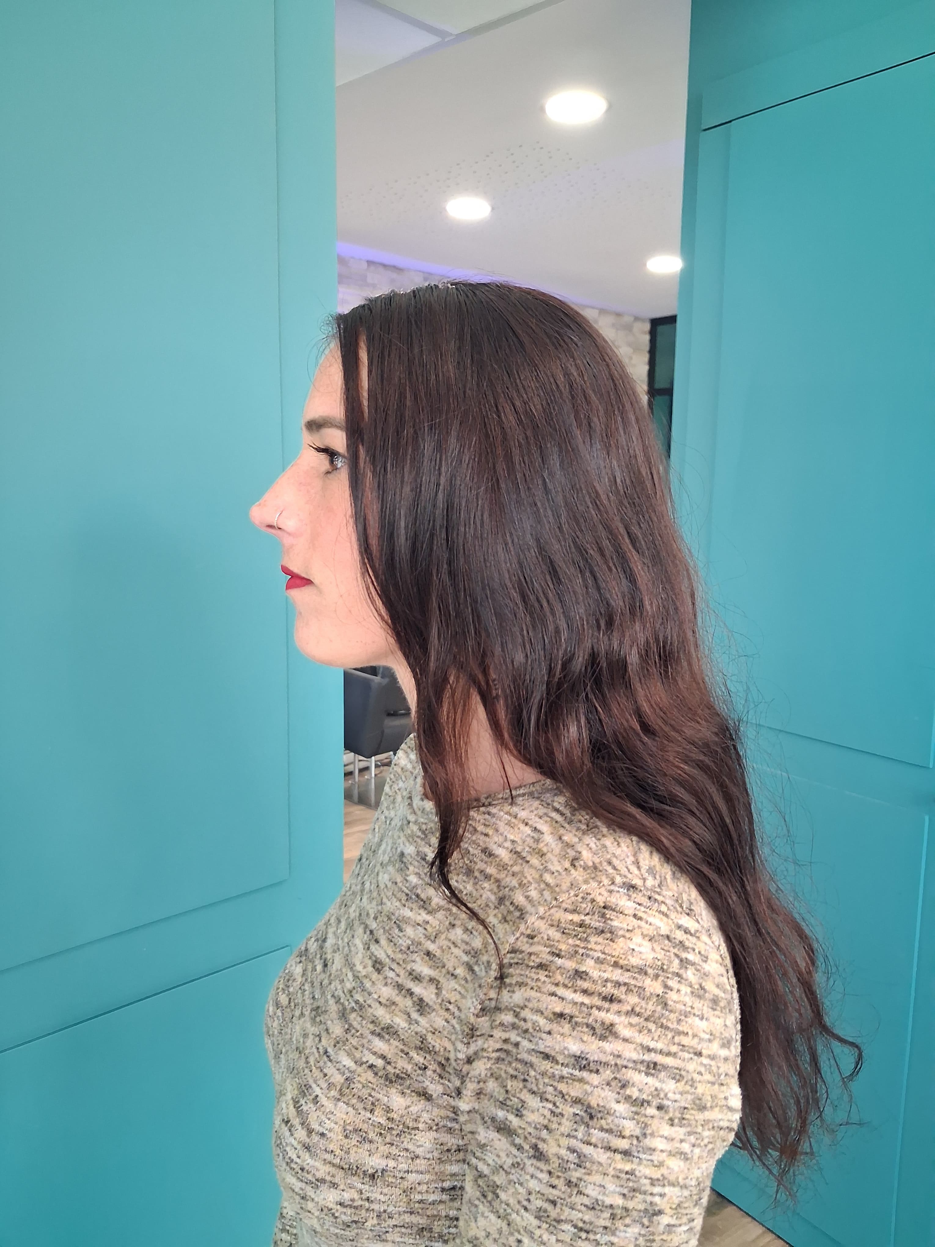 Cheveux longs, épais et ondulés vus de dos dans un salon de coiffure.