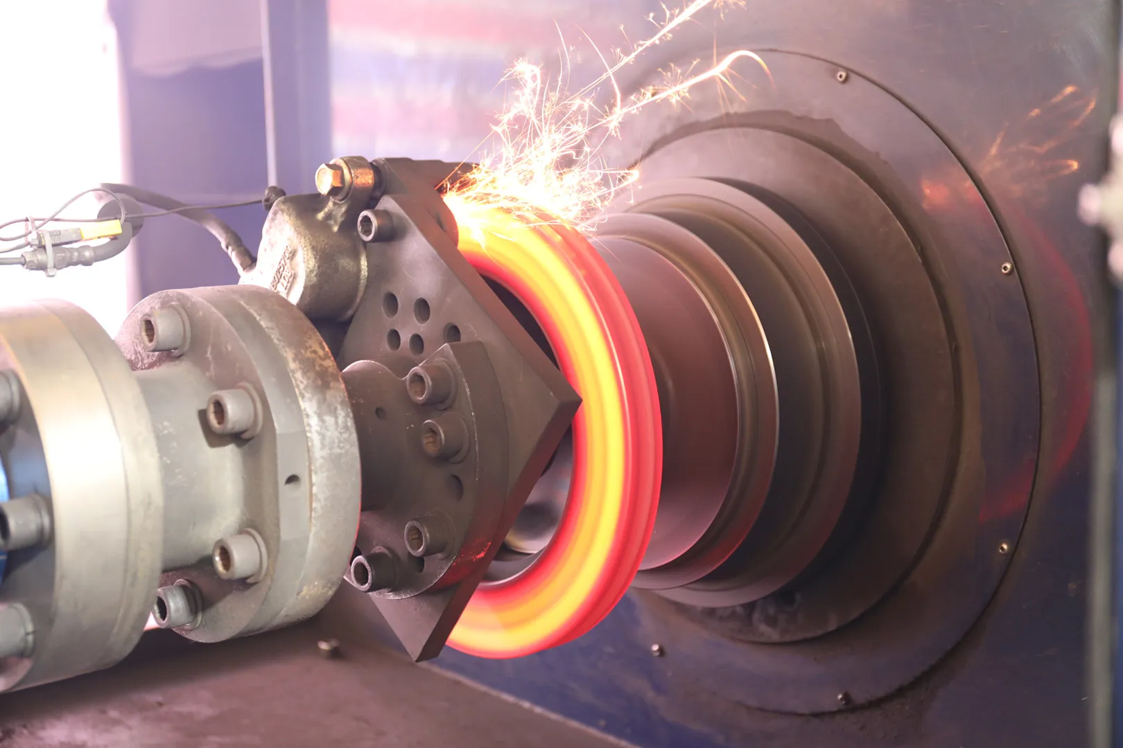 Close-up of a hot, glowing metal ring being machined with sparks flying.