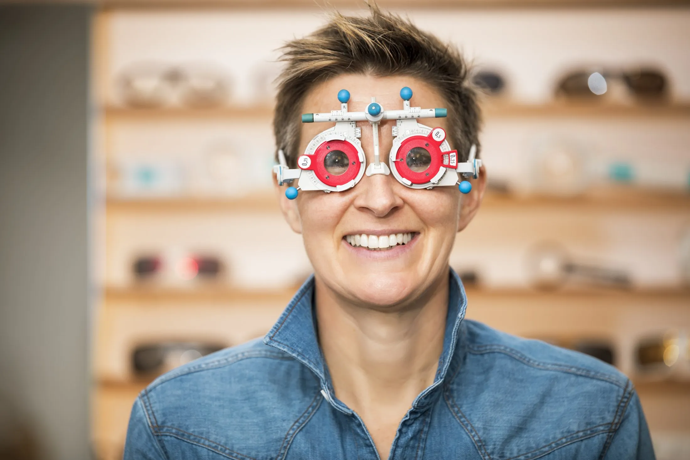 Smiling person wearing optometrist's trial frame during eye exam