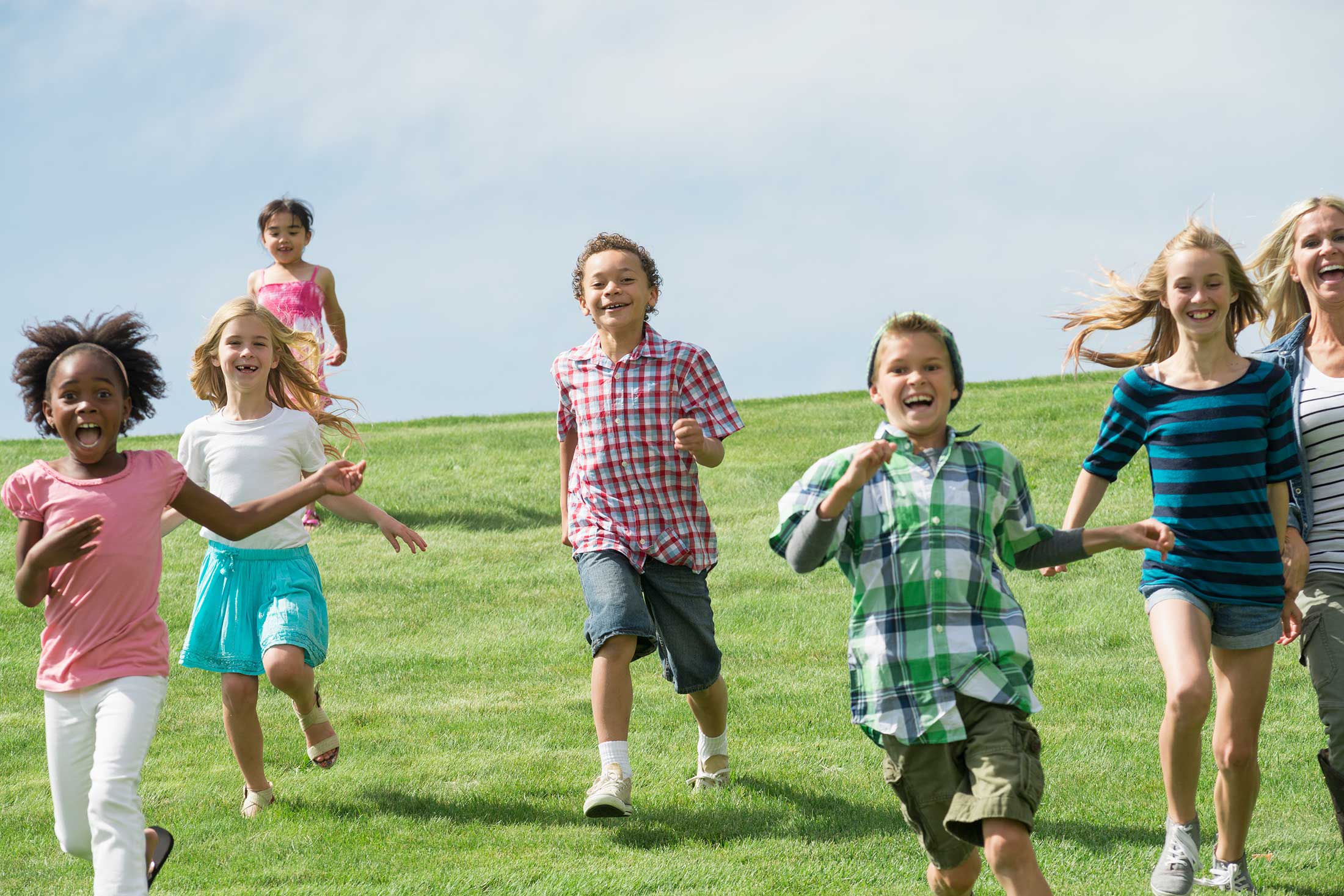 Diverse group of children running and playing together on green grass
