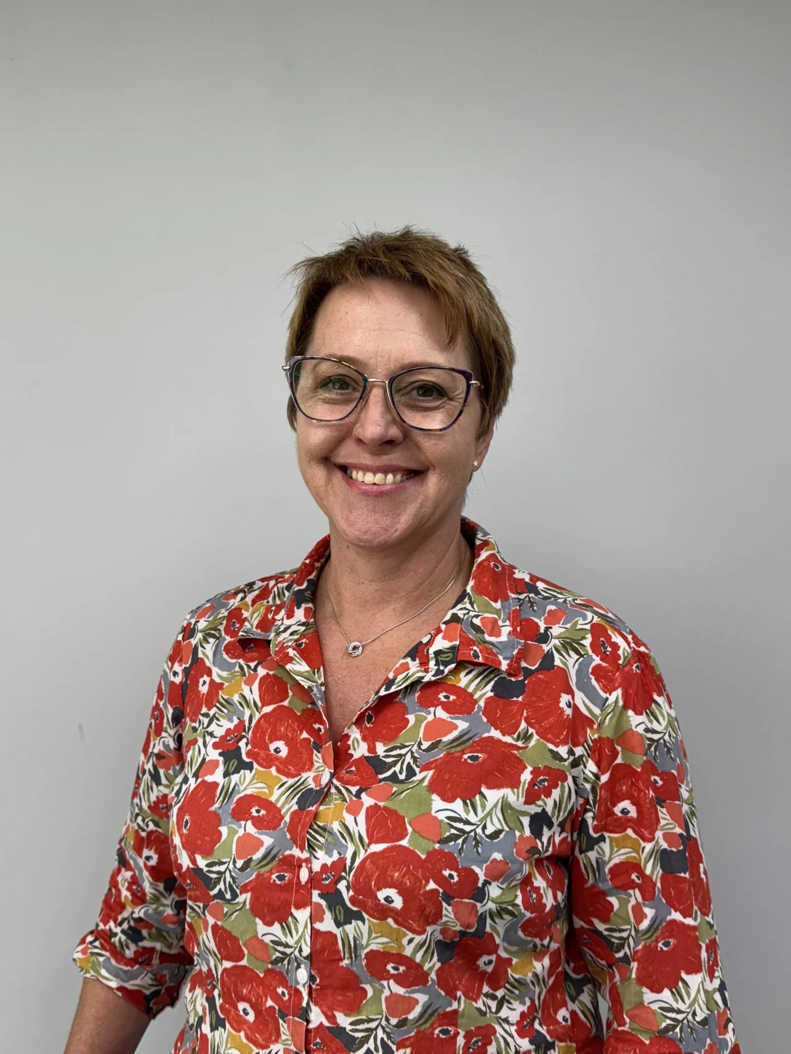 Smiling woman in glasses wearing a colorful floral print shirt