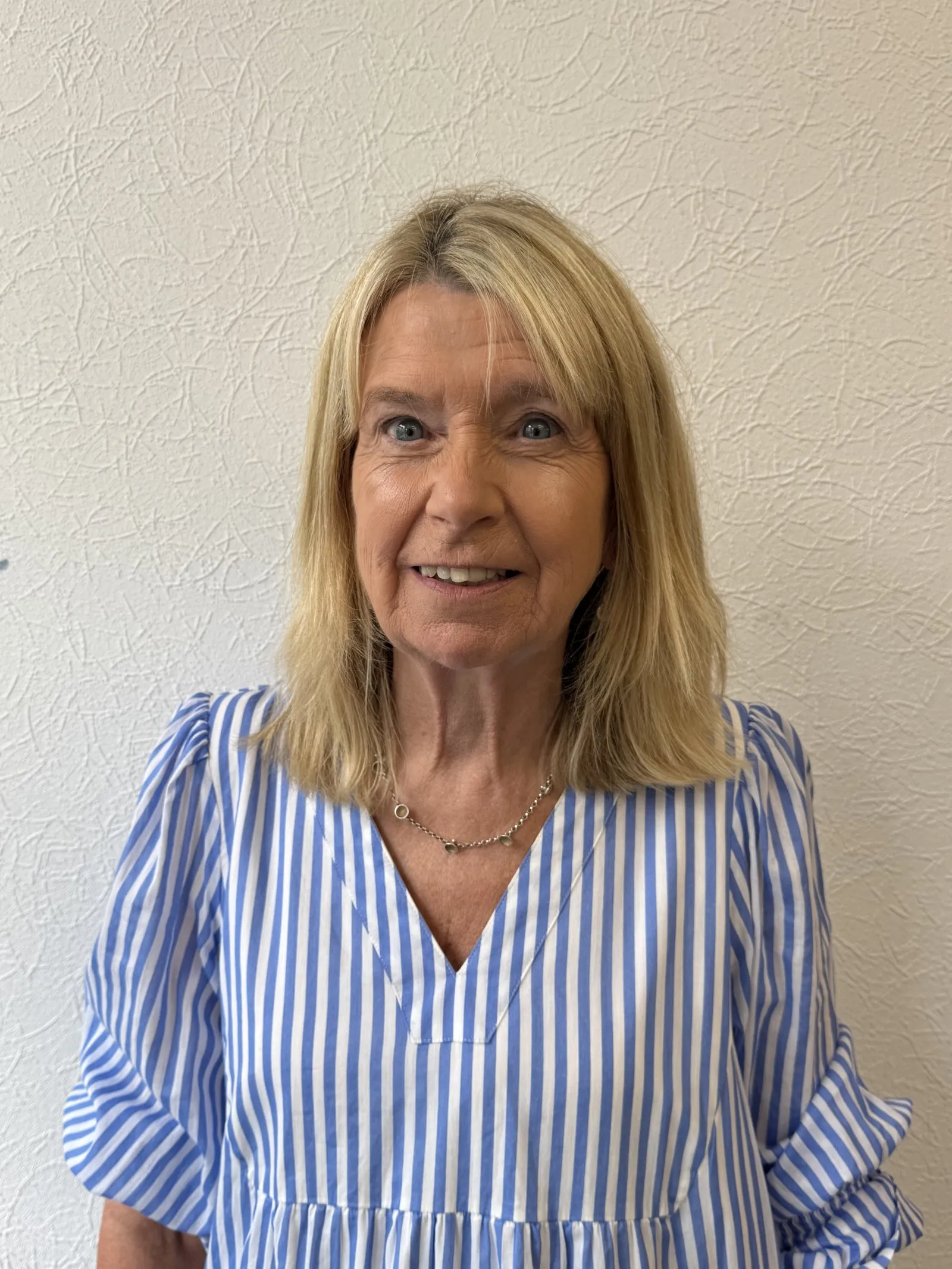 Older woman in blue and white striped top smiling at camera