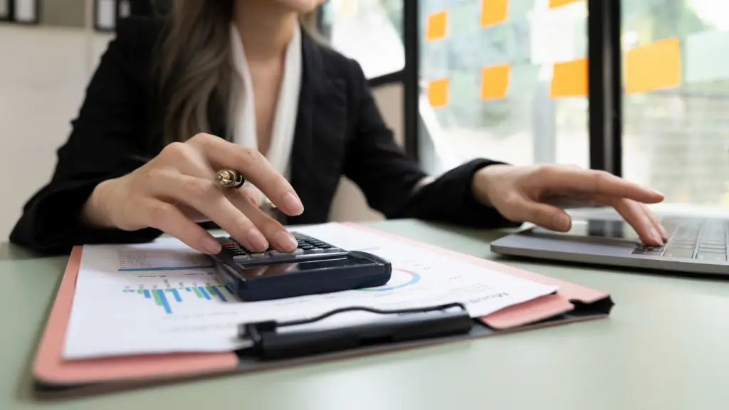 DRH utilisant une calculatrice et un ordinateur pour calculer une avance, un acompte, un prêt ou un indu sur salaire
