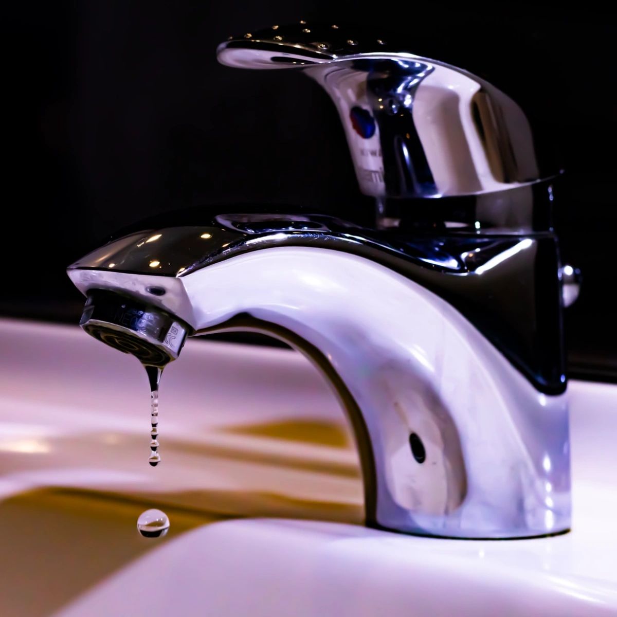 Close-up of a leaking faucet, showing a droplet of water forming, illustrating the need for faucet repair or installation services in Allen, TX.