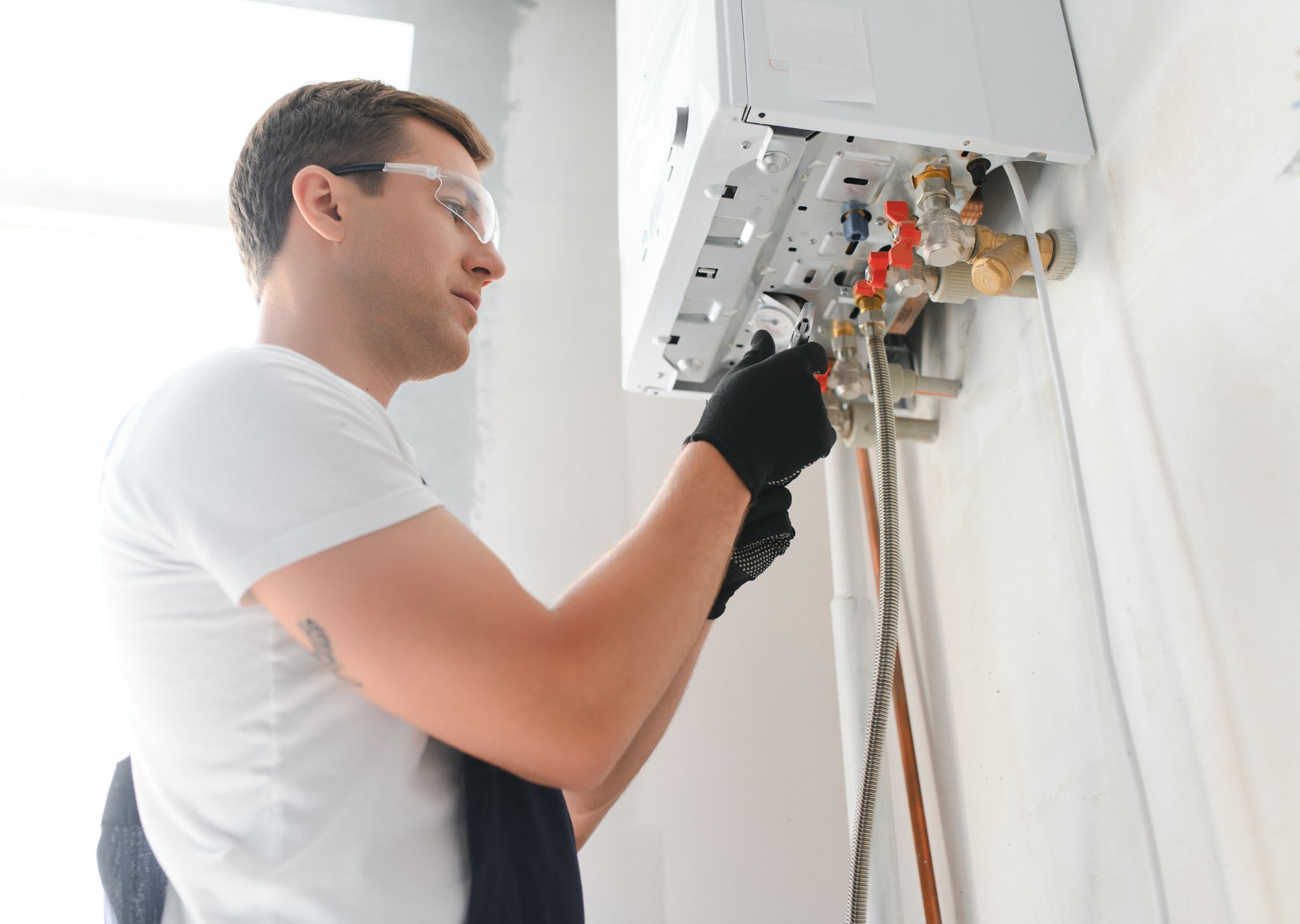 Plumber repairing a water heater valve and connection for safe operation.