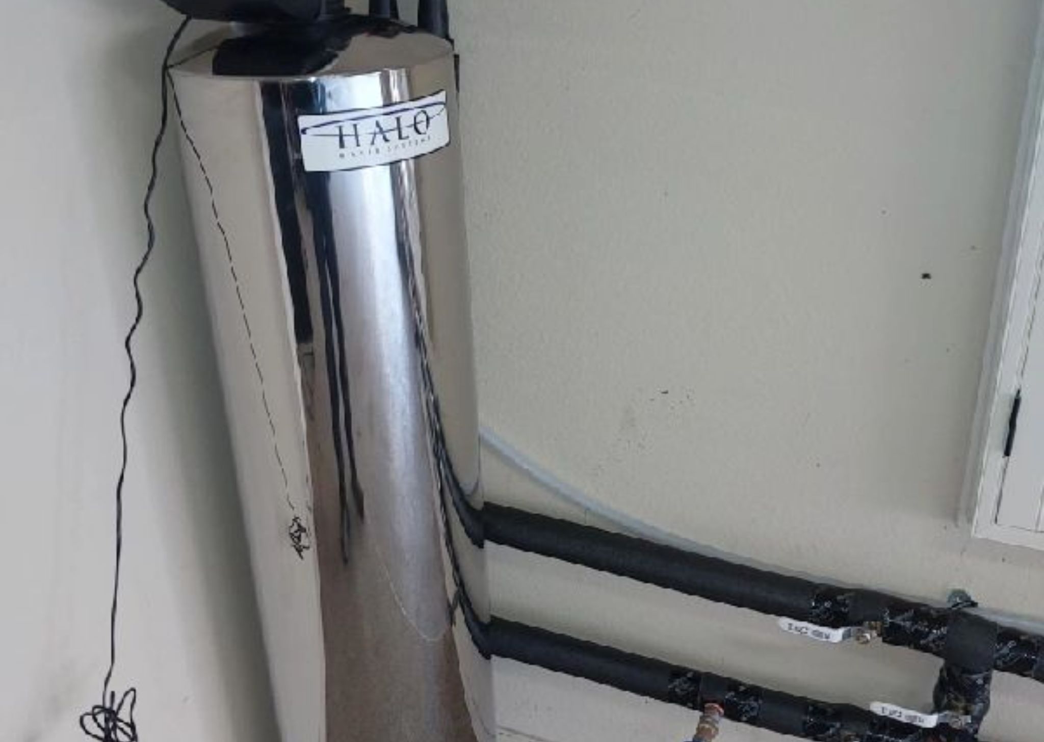 Technician installing an under-sink water filtration system in a kitchen cabinet.