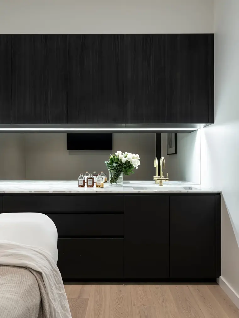 Black cabinetry, a marble counter and white flowers in the Sydney studio.