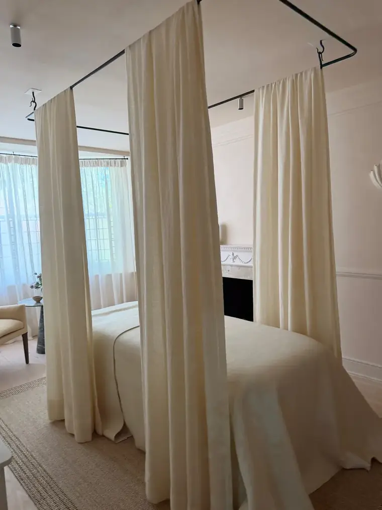 A London treatment room framed by light canopy curtains.