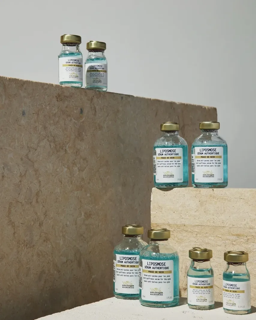 Glass vials of Biologique Recherche serum arranged on stone steps.