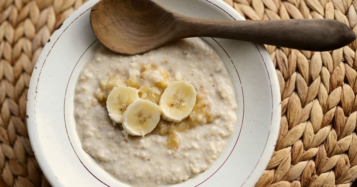 Bowl of oat porridge with spoon, illustrating oats and their effect on blood sugar and fullness