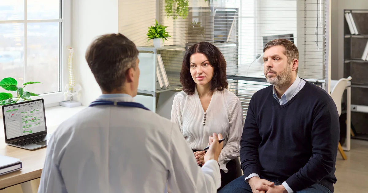 A man and his partner discussing weight loss treatment and family planning with a doctor during a clinical consultation