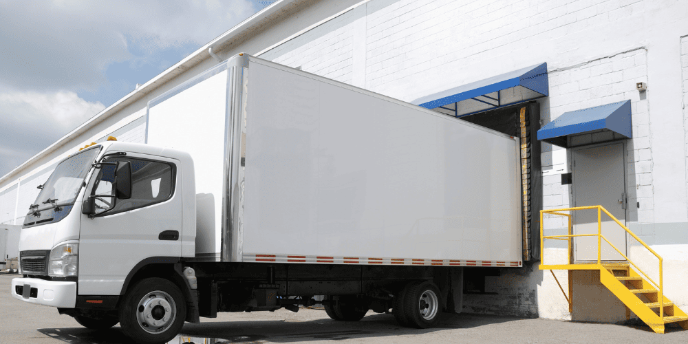 Movers securing filing cabinets with straps inside a truck